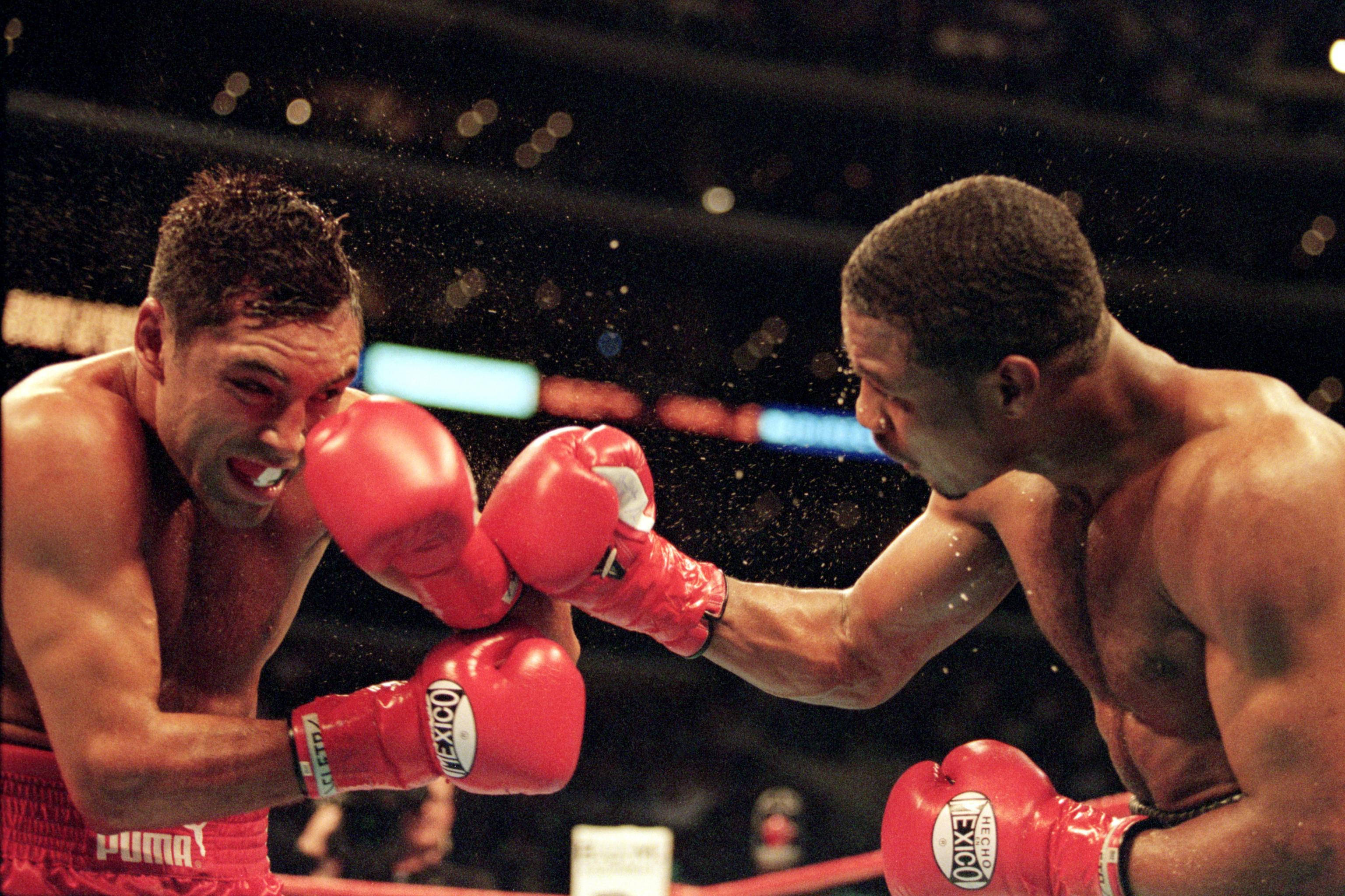 Boxing 桌布 壁紙 — 兩名拳擊手在濺滿雨水的擂台上，戴著紅色手套，在明亮的場館燈光下激烈對峙。