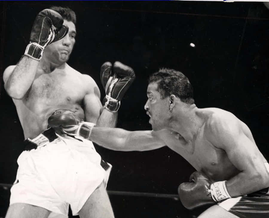 Boxing 桌布 壁紙 — 兩名拳擊手在粗糙的黑白擂台上碰撞，其中一人向對方的軀幹打出強力一拳。