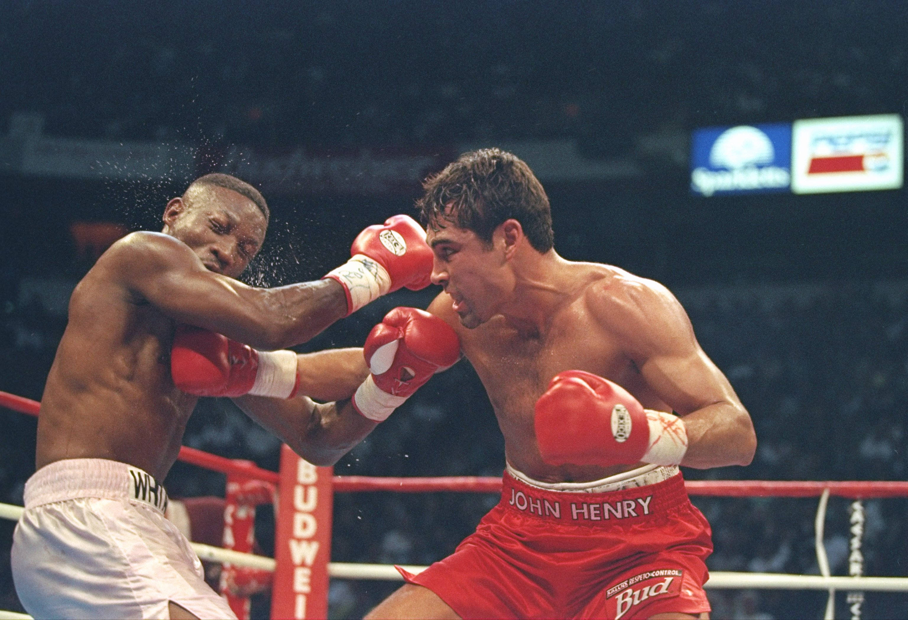 Boxing 桌布 壁紙 — 兩名拳擊手在雨水濺灑的擂台上交鋒，其中一人在明亮的場館燈光下向對方臉部擊出強力一拳。