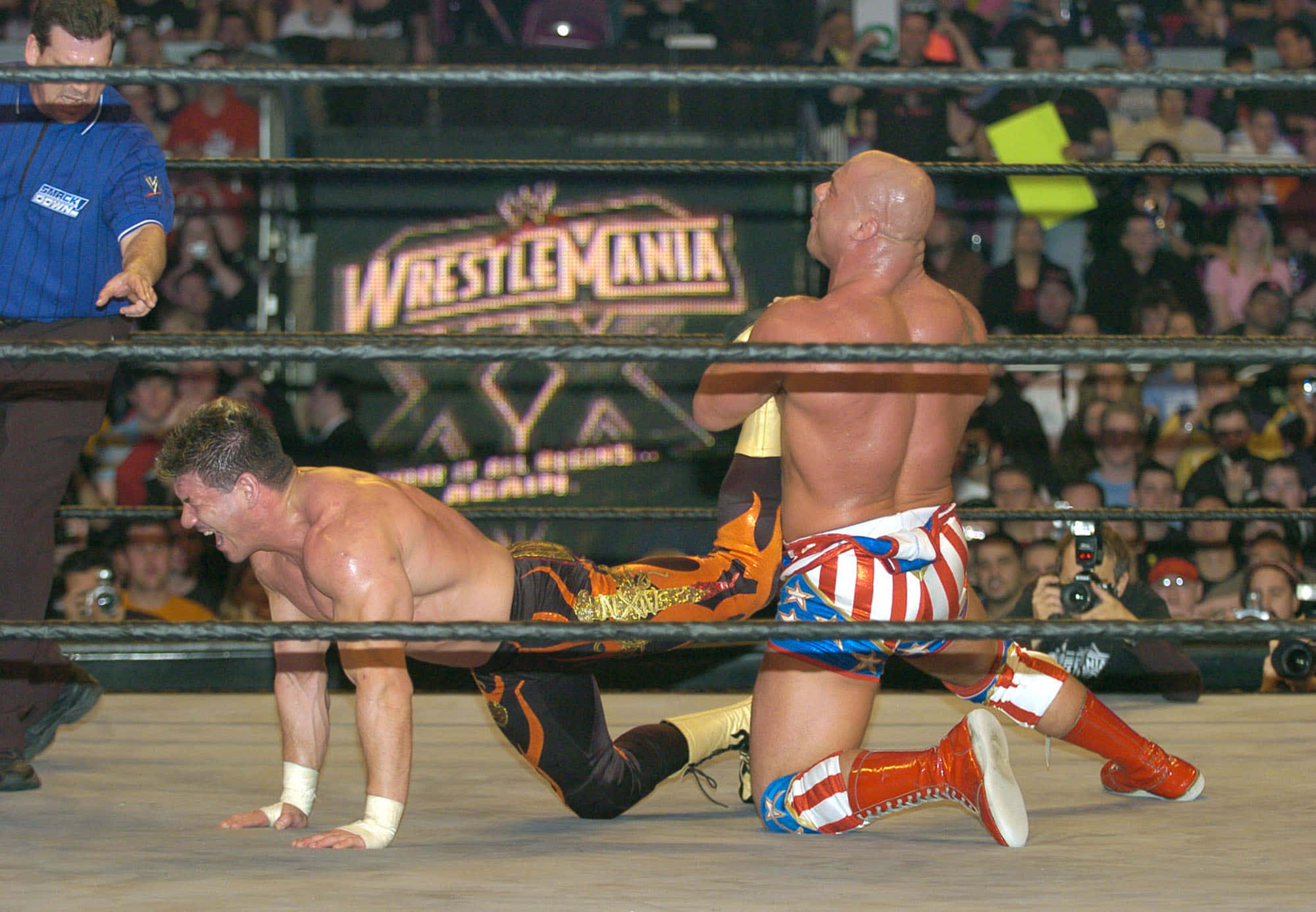 WWE 桌布 壁紙 — 兩名摔角手在WrestleMania的擂台上激烈纏鬥，裁判和觀眾在旁觀看。