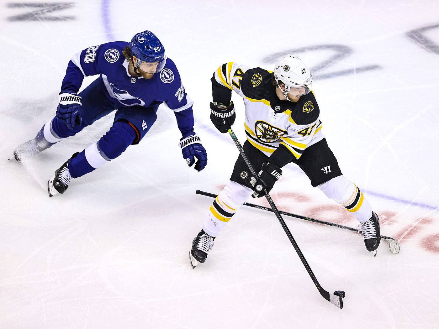 Tampa Bay Lightning 桌布 壁紙 — 兩名曲棍球運動員在佈滿劃痕的冰場上，在明亮的場館燈光下激烈爭奪球權。