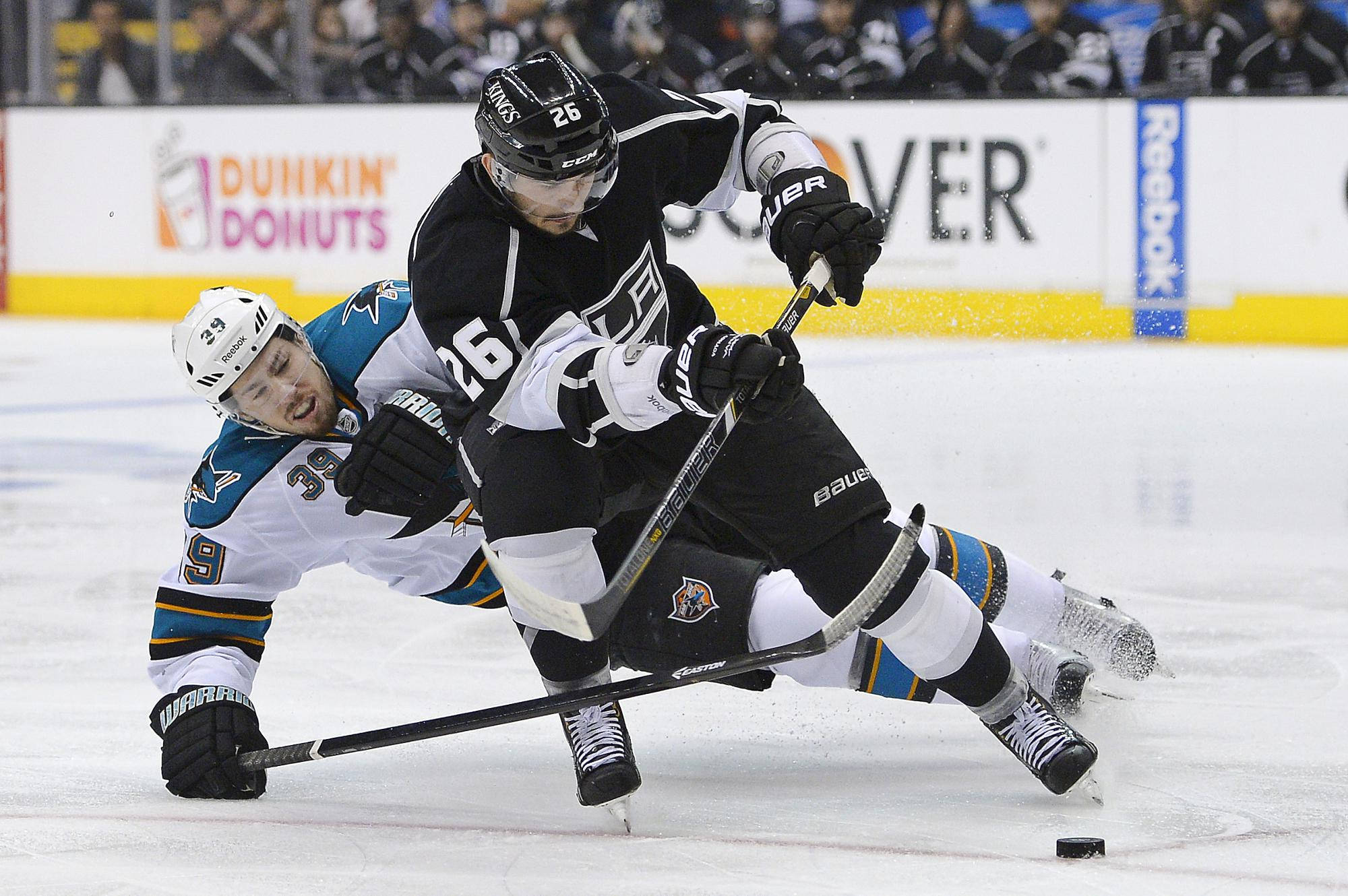 Los Angeles Kings 桌布 壁紙 — 兩名曲棍球運動員在冰上激烈對戰，手持球桿、腳踏冰刀，進行一場快節奏的比賽。
