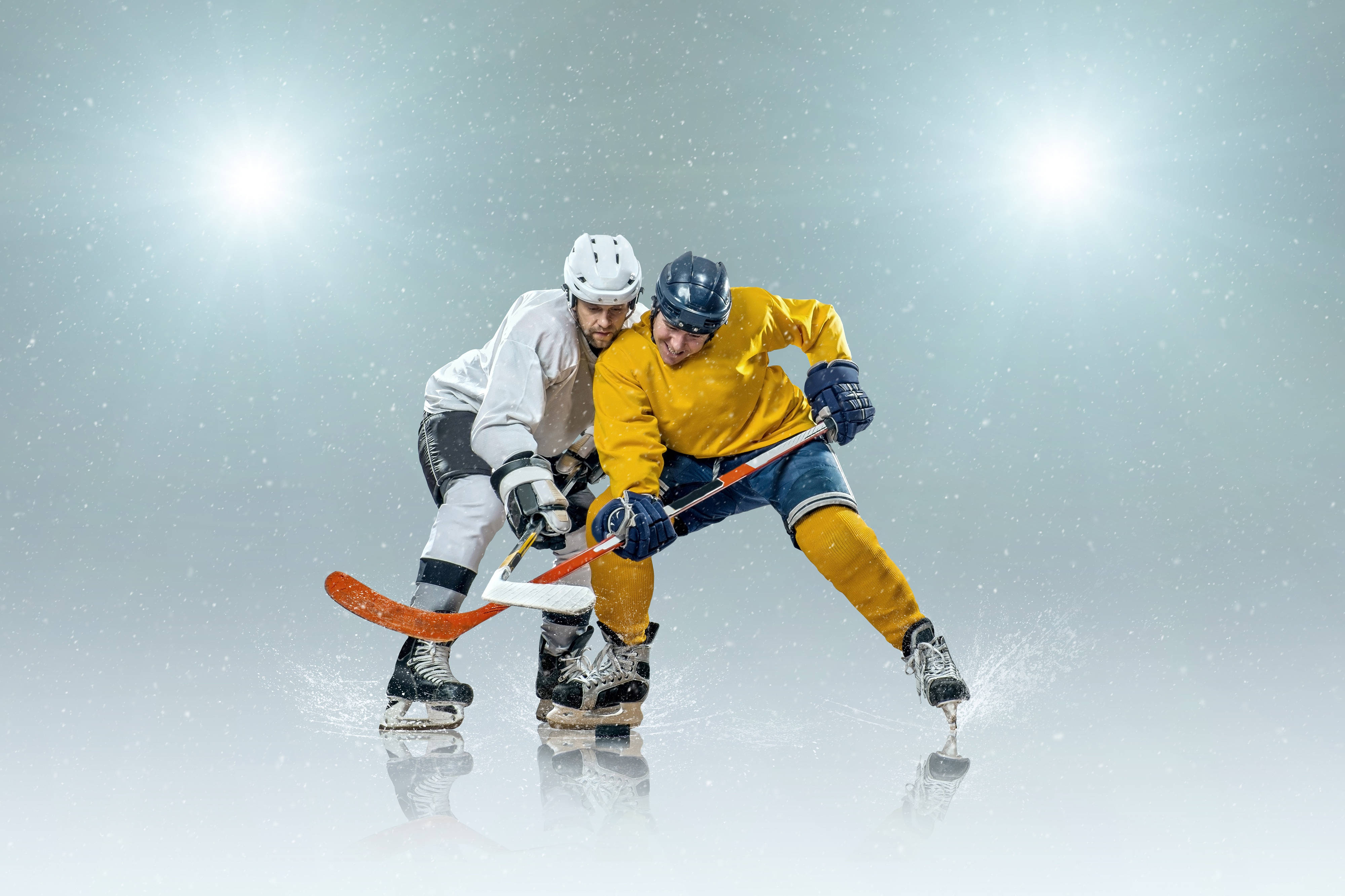 hockey 桌布 壁紙 — 兩名曲棍球運動員在明亮的場館燈光下，雪花飄落中，在冰上激烈對戰。