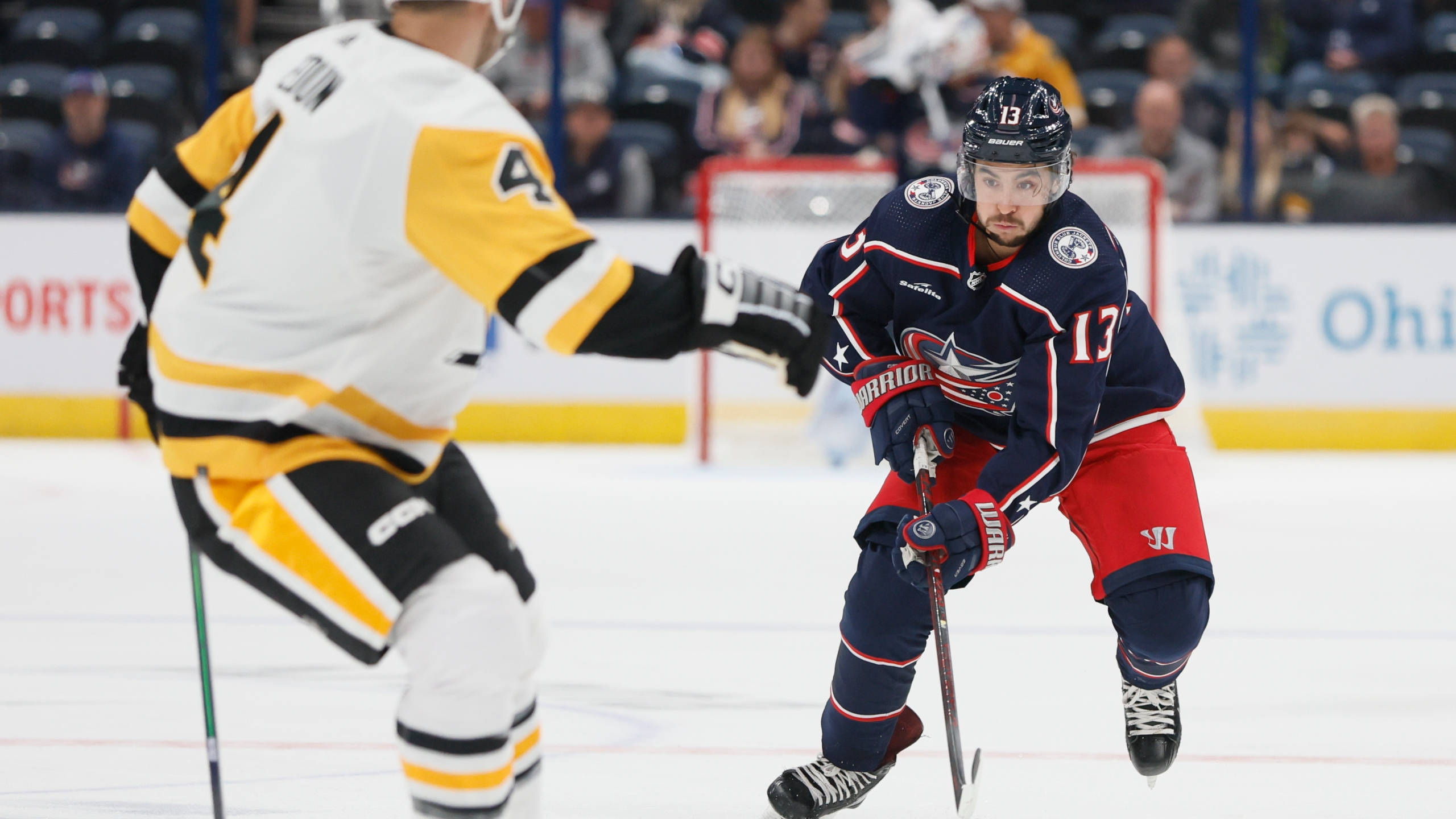 Columbus Blue Jackets 桌布 壁紙 — 兩名曲棍球運動員在燈光明亮的冰場上，於職業比賽中激烈爭奪冰球。
