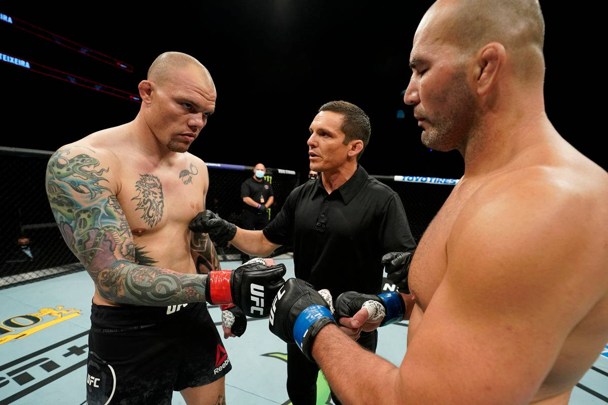 MMA 桌布 壁紙 — 兩名有刺青的MMA拳手在鐵籠中對峙，裁判在比賽前握住他們的手。