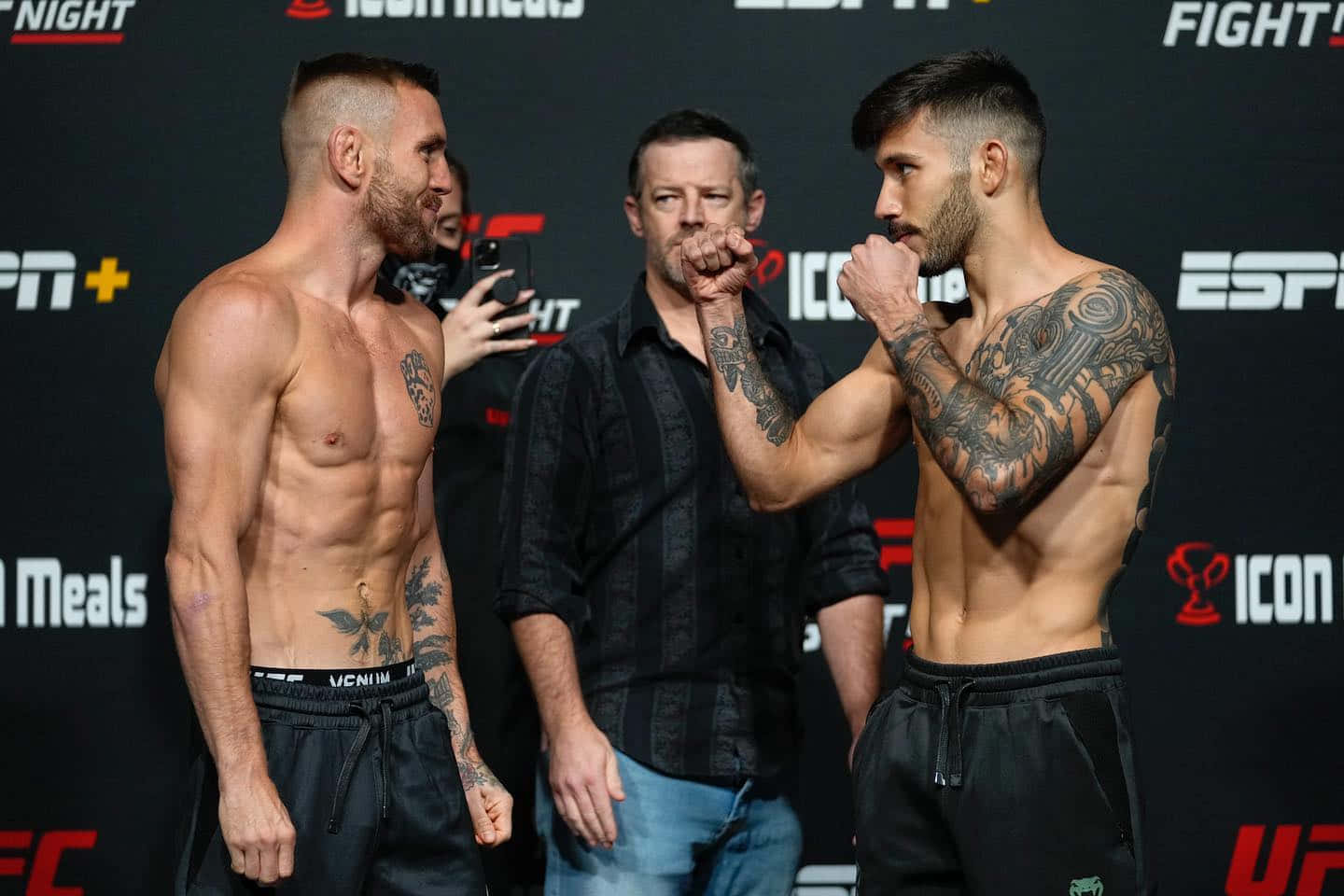 MMA 桌布 壁紙 — 兩名有刺青的UFC拳手在ESPN品牌背景的過磅活動中激烈對峙。