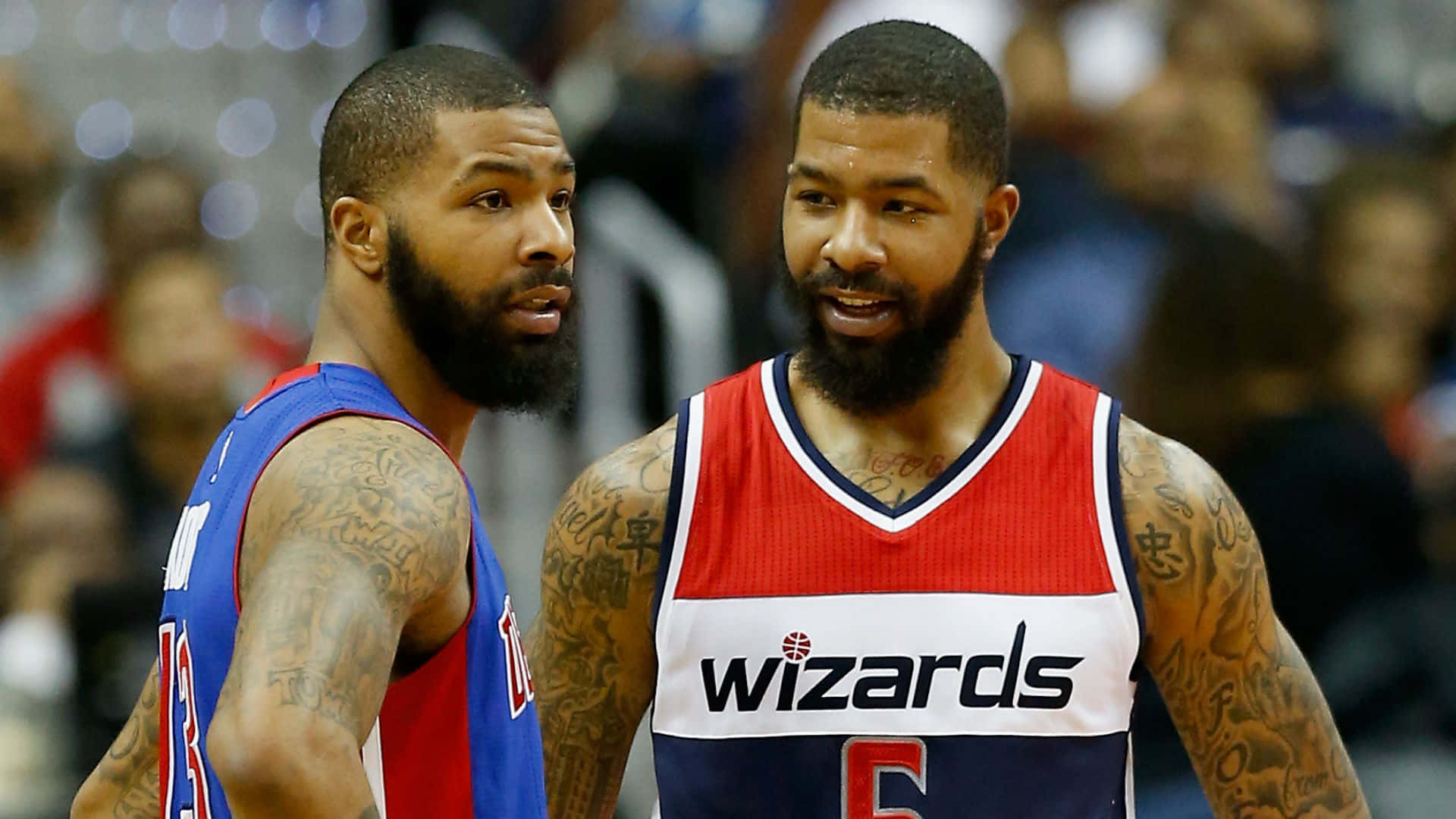 NBA 桌布 壁紙 — 兩名有刺青的籃球運動員穿著球隊球衣，在比賽中激烈交談，背景是模糊的人群。