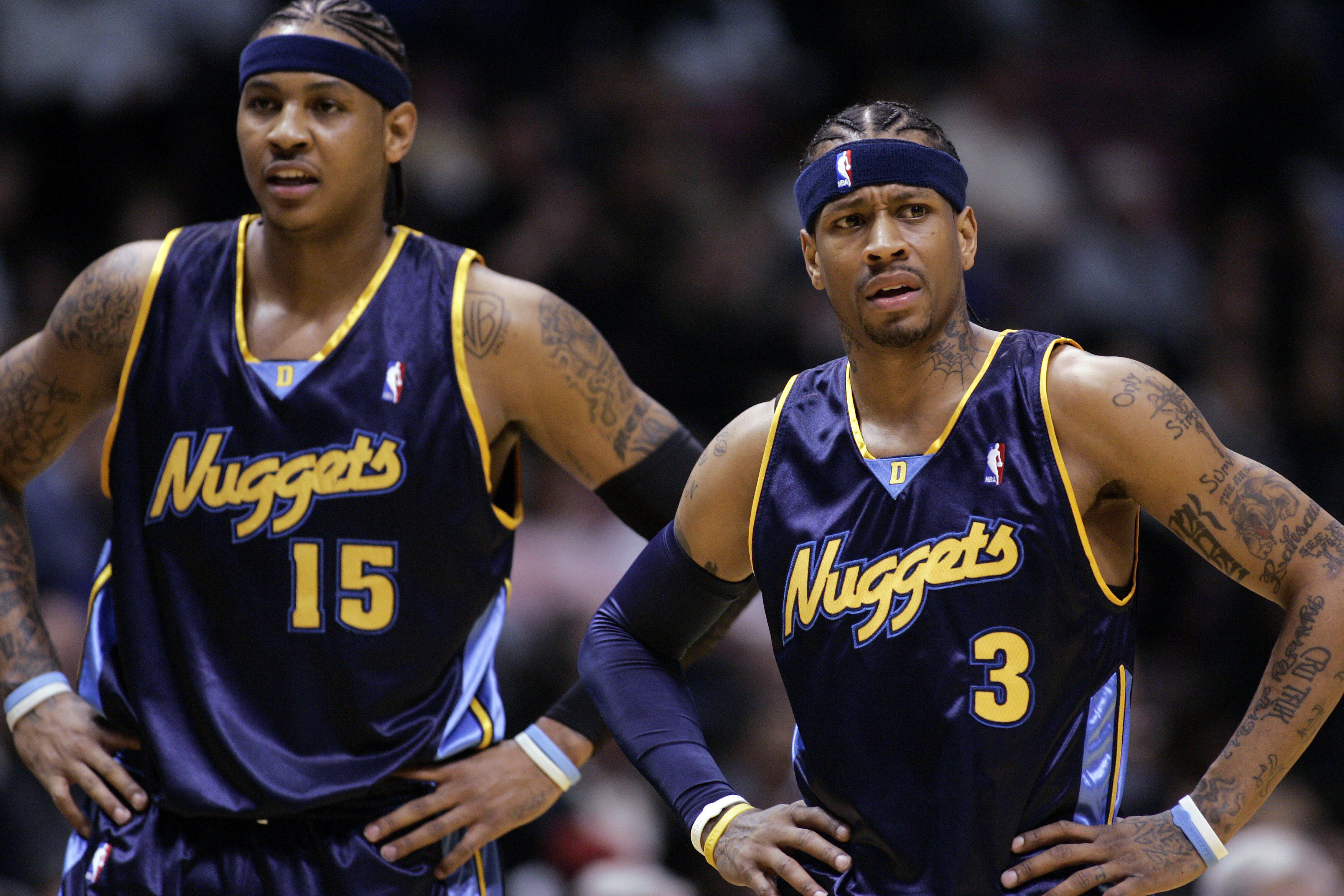 Carmelo 桌布 壁紙 — 兩名有刺青的籃球運動員穿著紫色金塊隊球衣，在明亮的場館燈光下比賽時雙手叉腰站立。