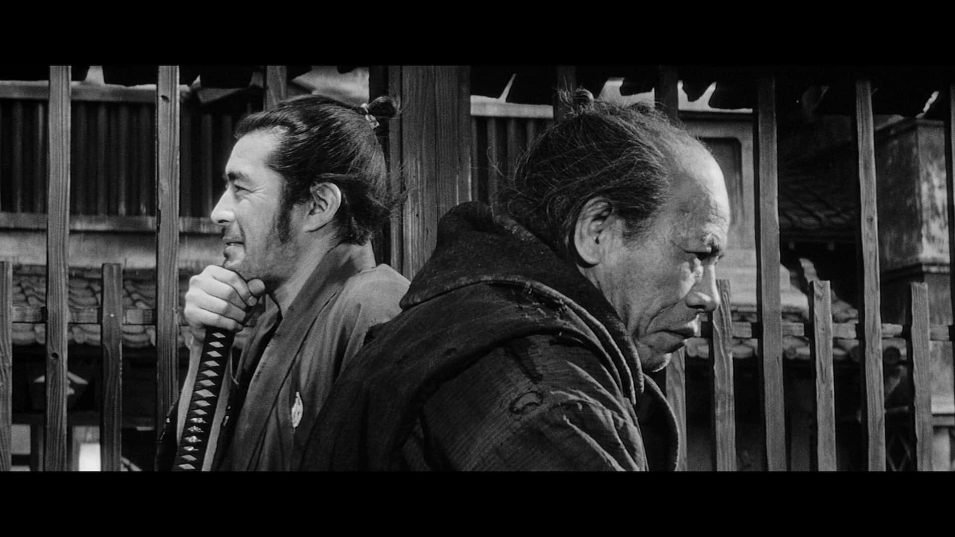 Samurai Movies 桌布 壁紙 — 兩名武士側身站在木條前，一人手持武士刀，另一人直視前方，黑白風格