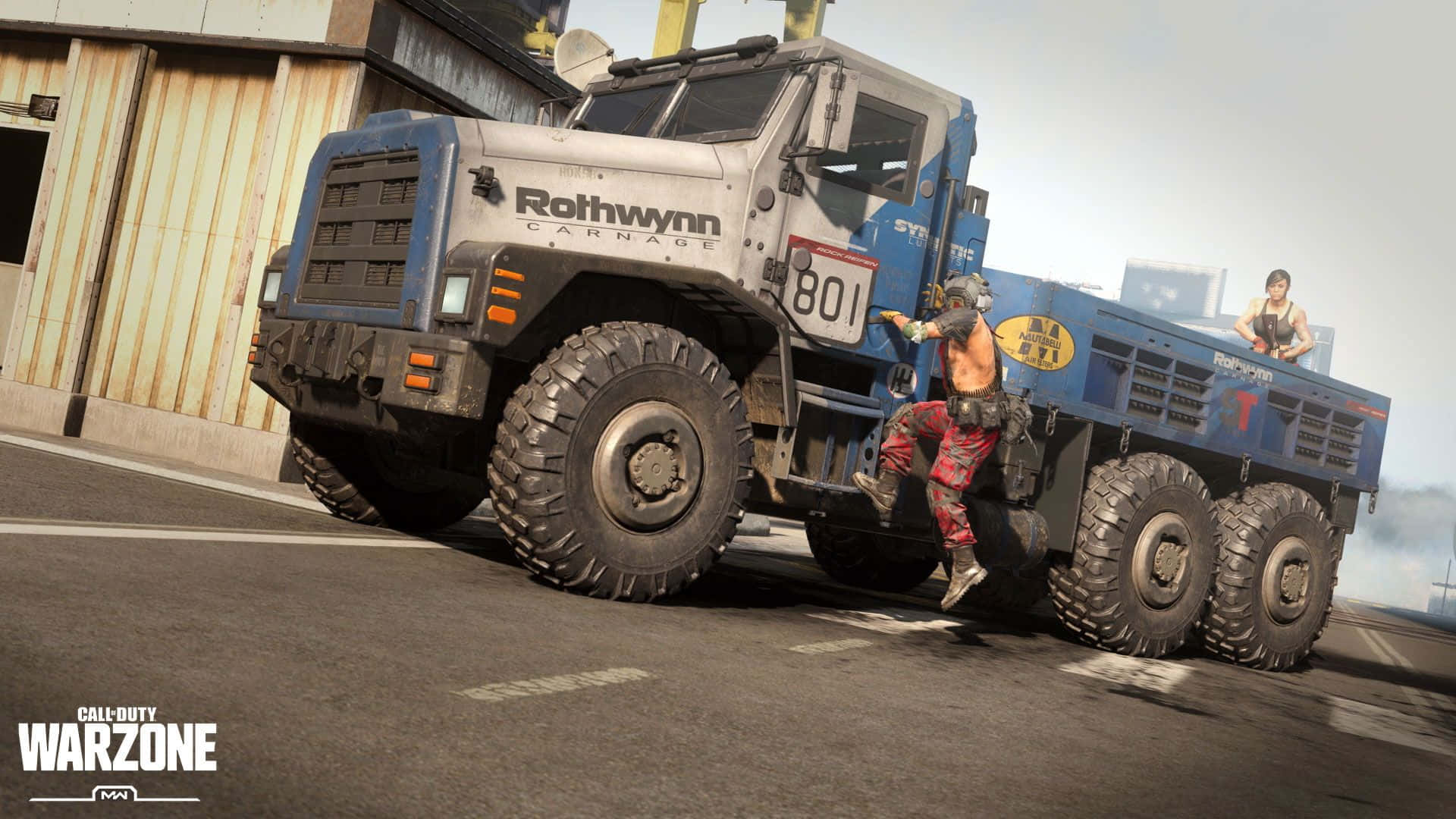 Call Of Duty Vehicles 桌布 壁紙 — 兩名武裝玩家爬上停在瀝青場地上、靠近波紋金屬建築的巨大藍色Rothwynn Carnage卡車。