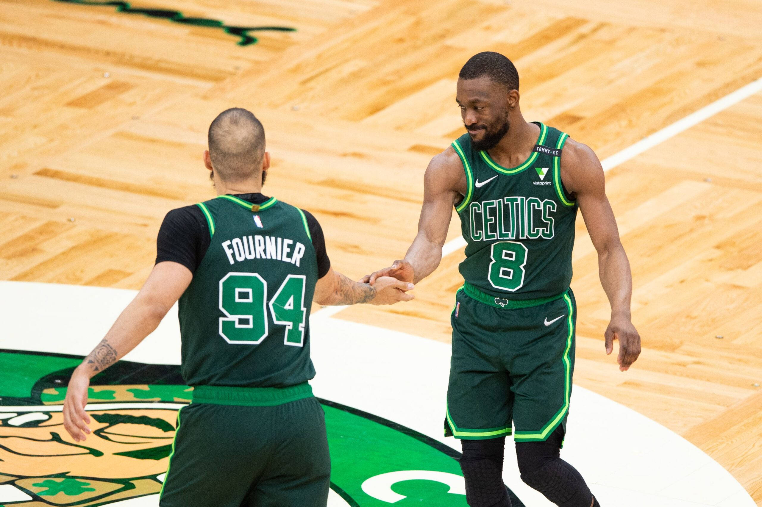 NBA 桌布 壁紙 — 兩名波士頓塞爾提克籃球運動員在拋光木地板上握手，球隊標誌清晰可見。