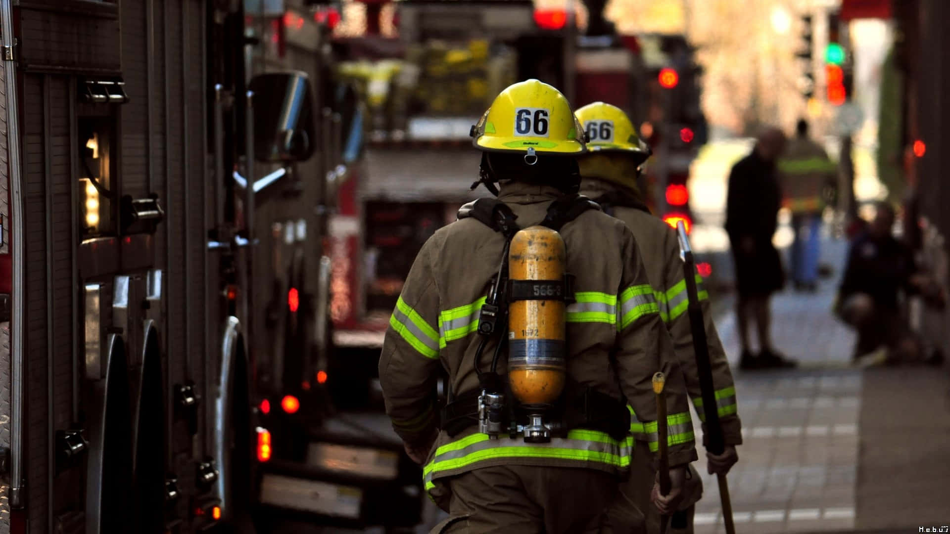 Fire Department 桌布 壁紙 — 兩名消防員戴著黃色頭盔和反光裝備，在夜間沿著城市街道從消防車走開。