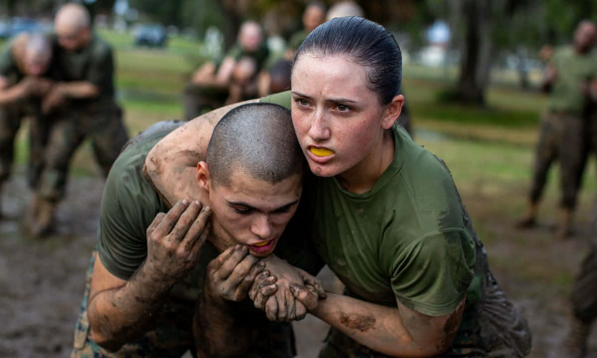 Marines 桌布 壁紙 — 兩名滿身泥濘的新兵在陰天下一同奮力通過艱苦的障礙訓練場。