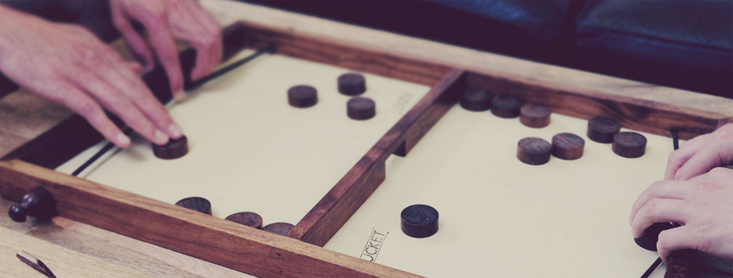 game 桌布 壁紙 — 兩名玩家在淺米色表面上激烈競爭一個帶有深色圓形棋子的木製棋盤遊戲。