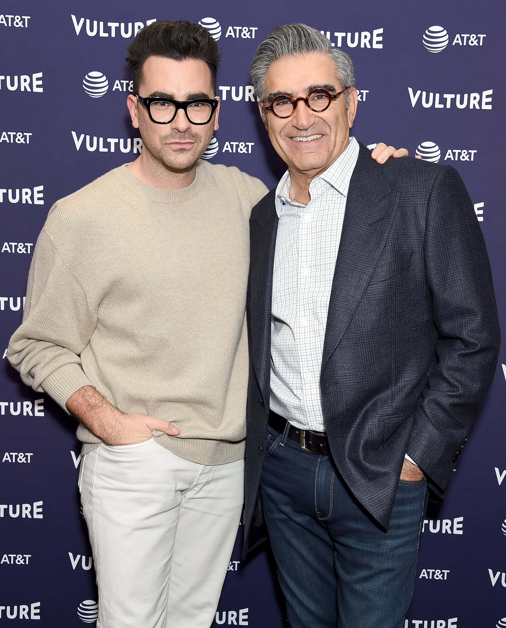 Eugene Levy 桌布 壁紙 — 兩名男子在一個Vulture活動中一起擺姿勢，背景是深藍色帶有AT&T標誌。