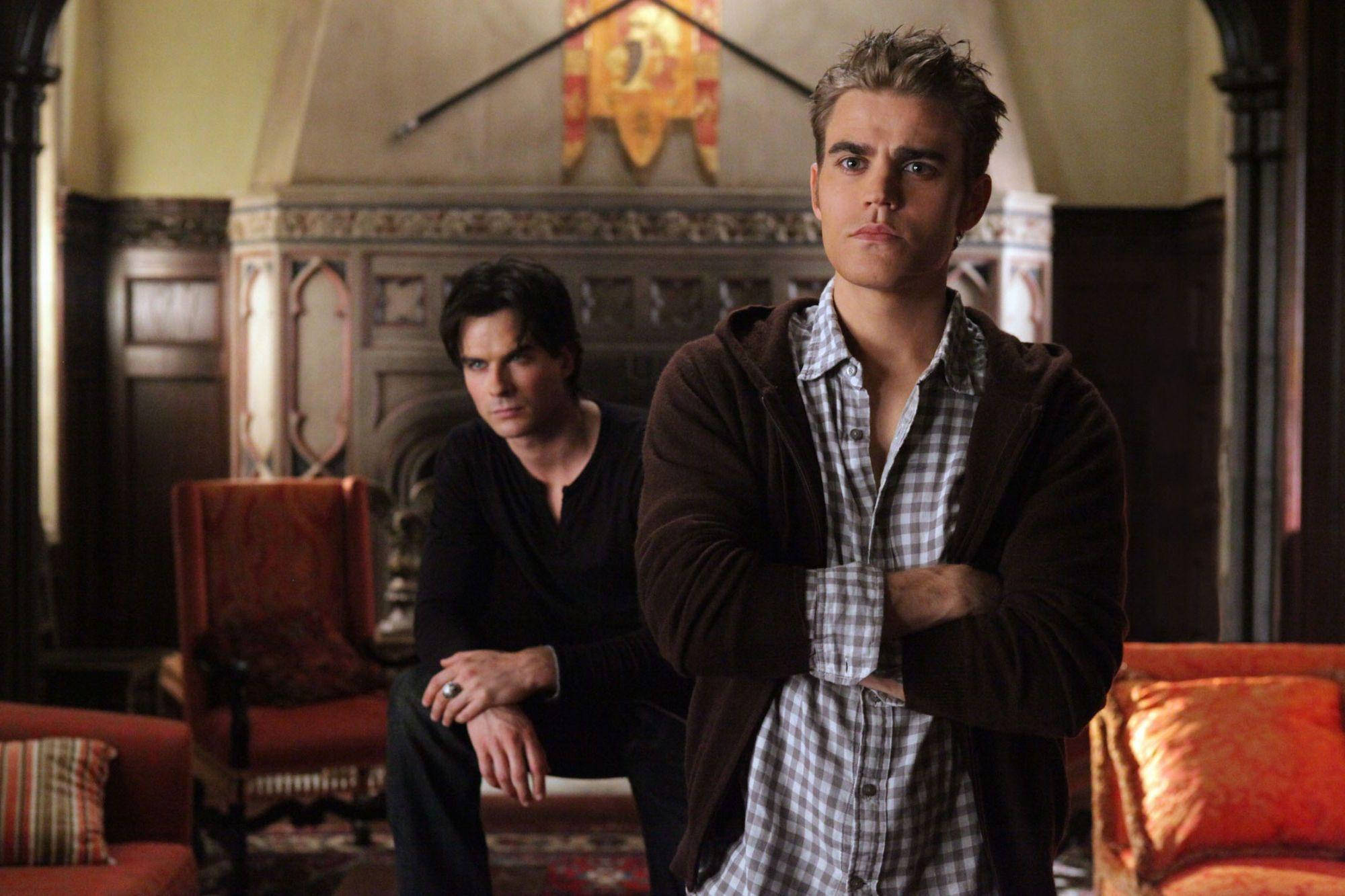 Damon Salvatore 桌布 壁紙 — 兩名男子在哥德式豪宅中，在華麗家具和溫暖燈光下，帶著嚴肅表情休息。