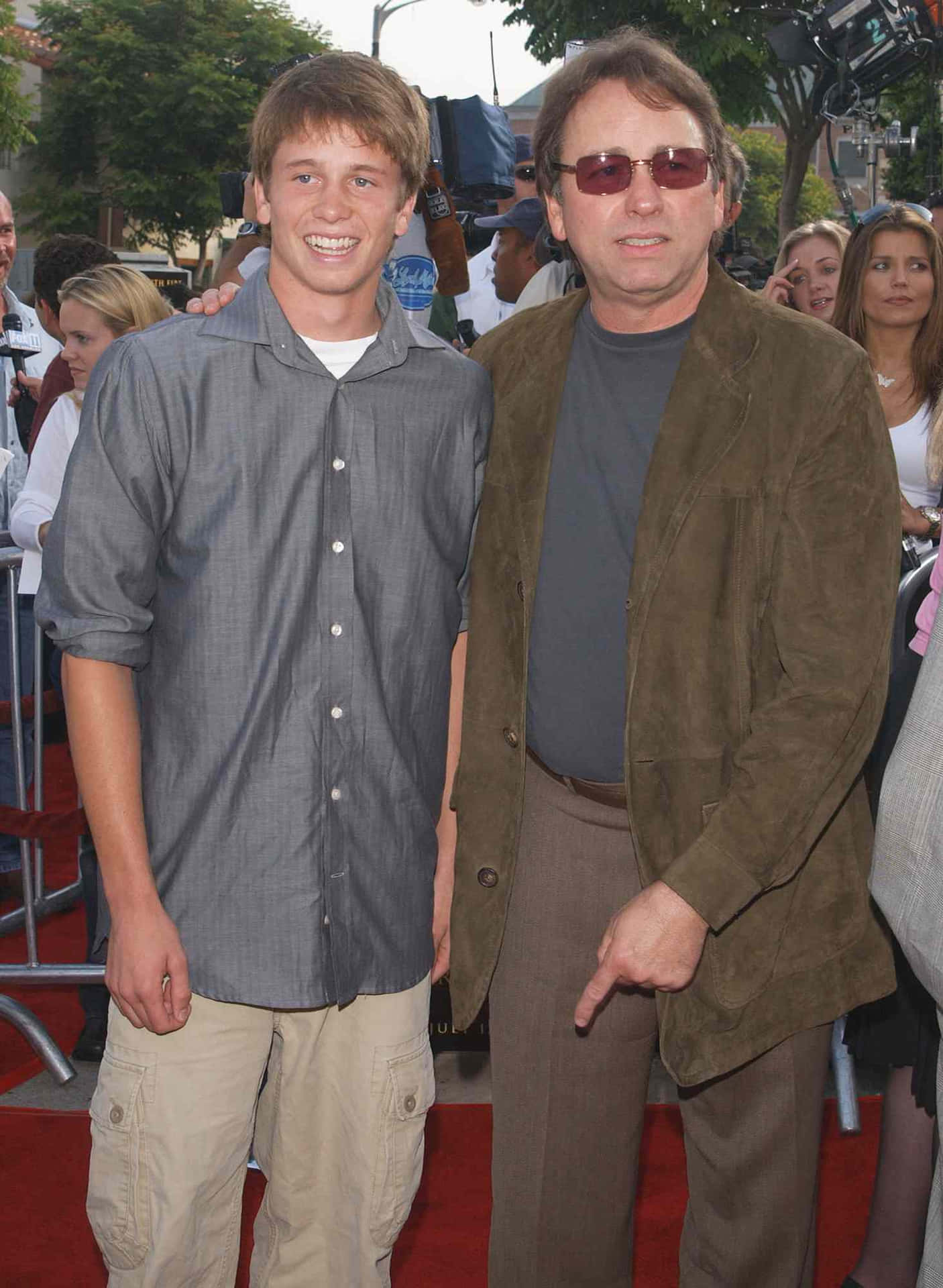 John Ritter 桌布 壁紙 — 兩名男子在戶外活動的紅地毯上微笑站立，身後有相機和人群。