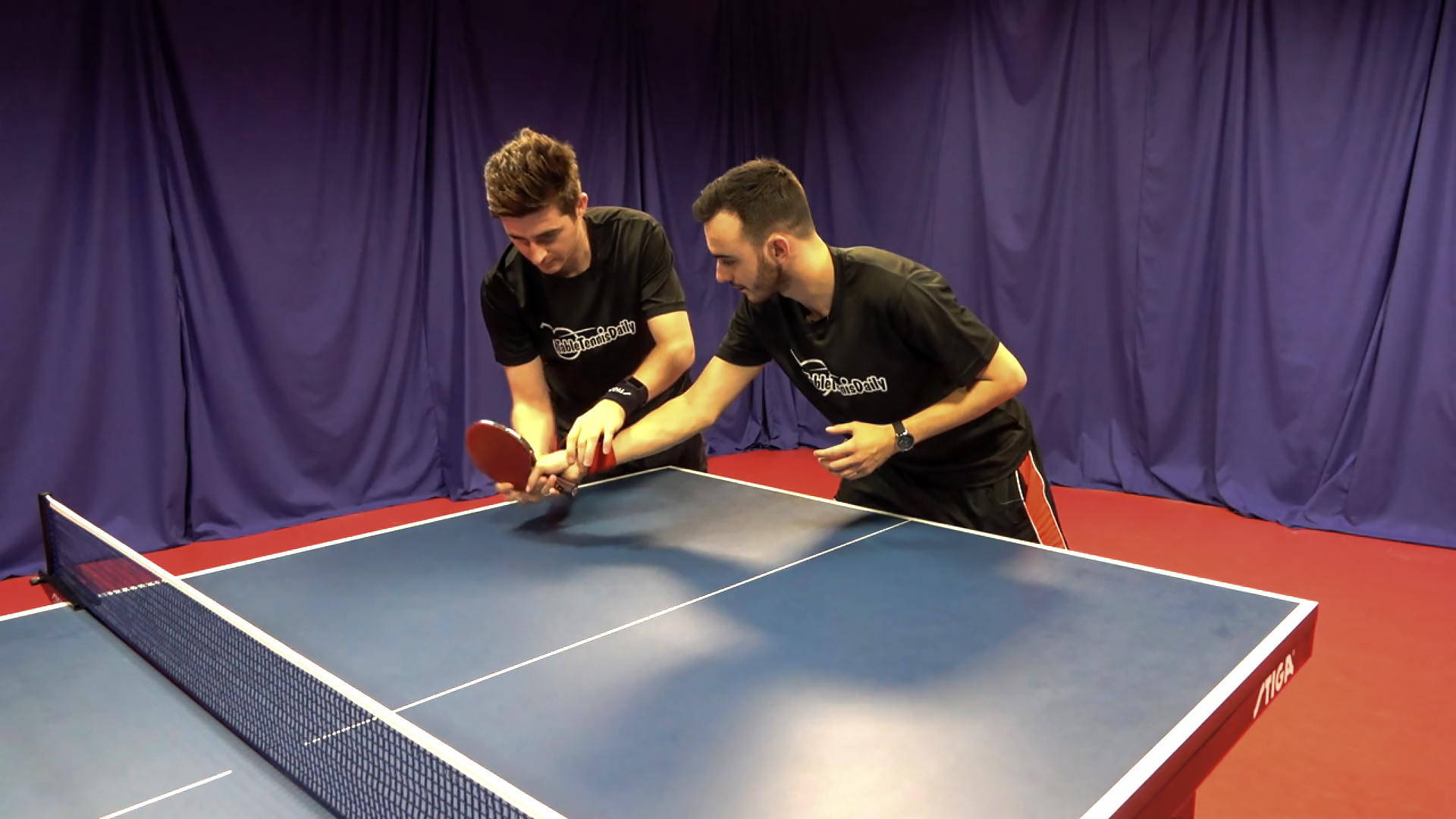 Table Tennis 桌布 壁紙 — 兩名男子在深紫色窗簾背景下專注於室內乒乓球比賽。