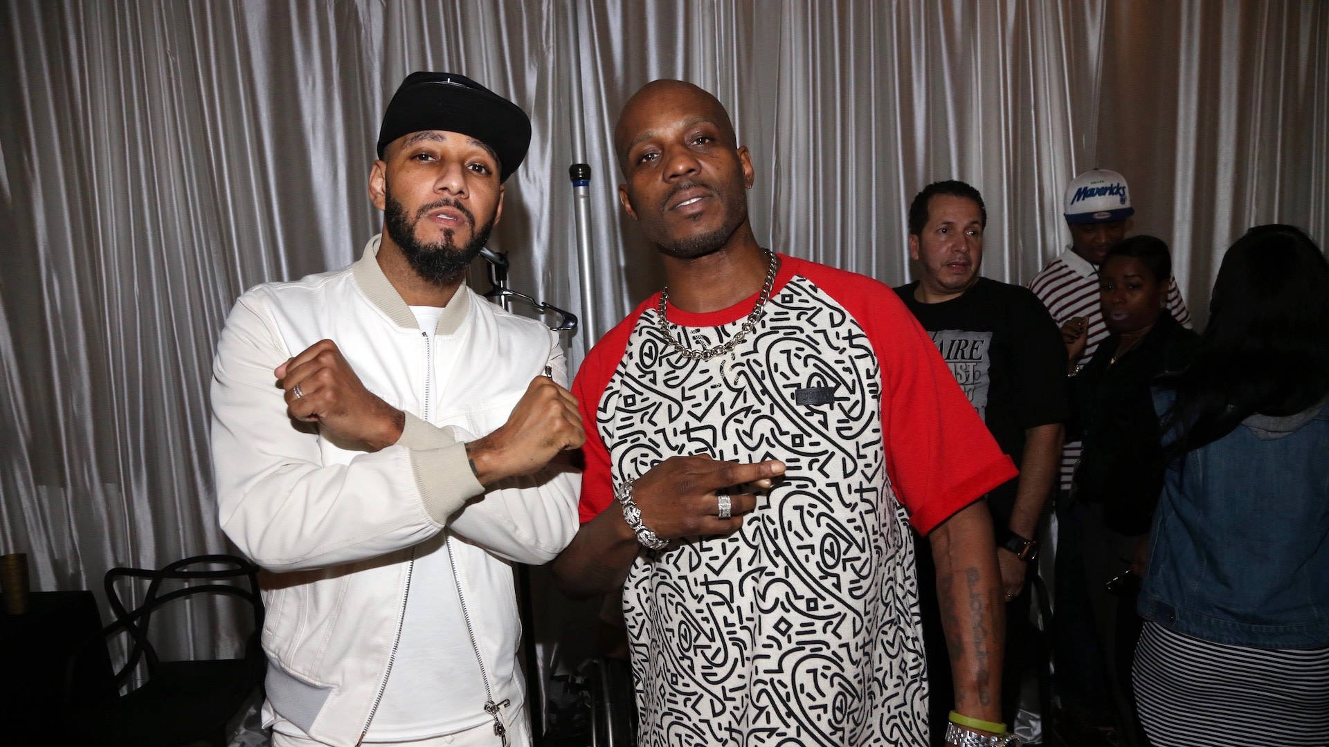 DMX 桌布 壁紙 — 兩名男子在燈光昏暗的室內活動中，自信地在垂簾前擺姿勢，背景有其他賓客。