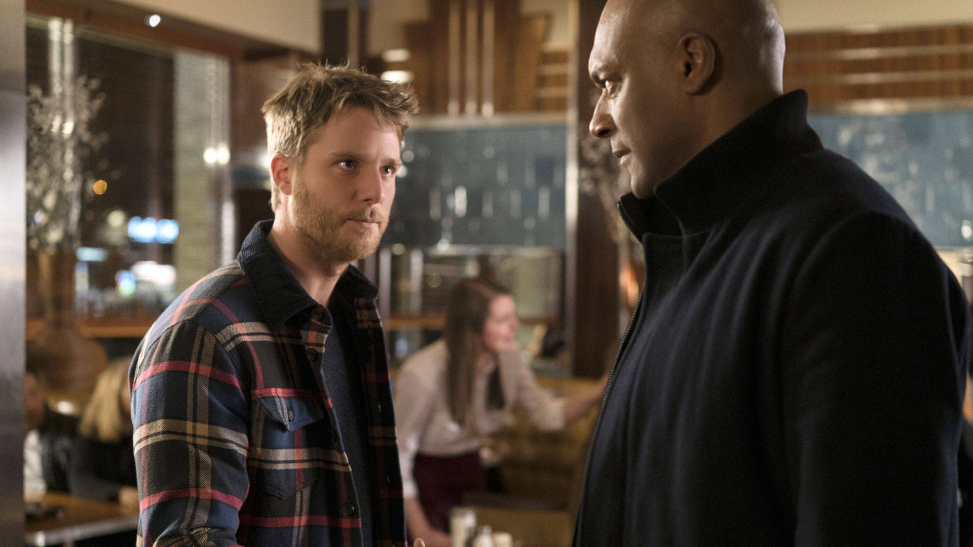 Colin Salmon 桌布 壁紙 — 兩名男子在燈光溫暖的餐廳中對峙，背景有模糊的顧客。