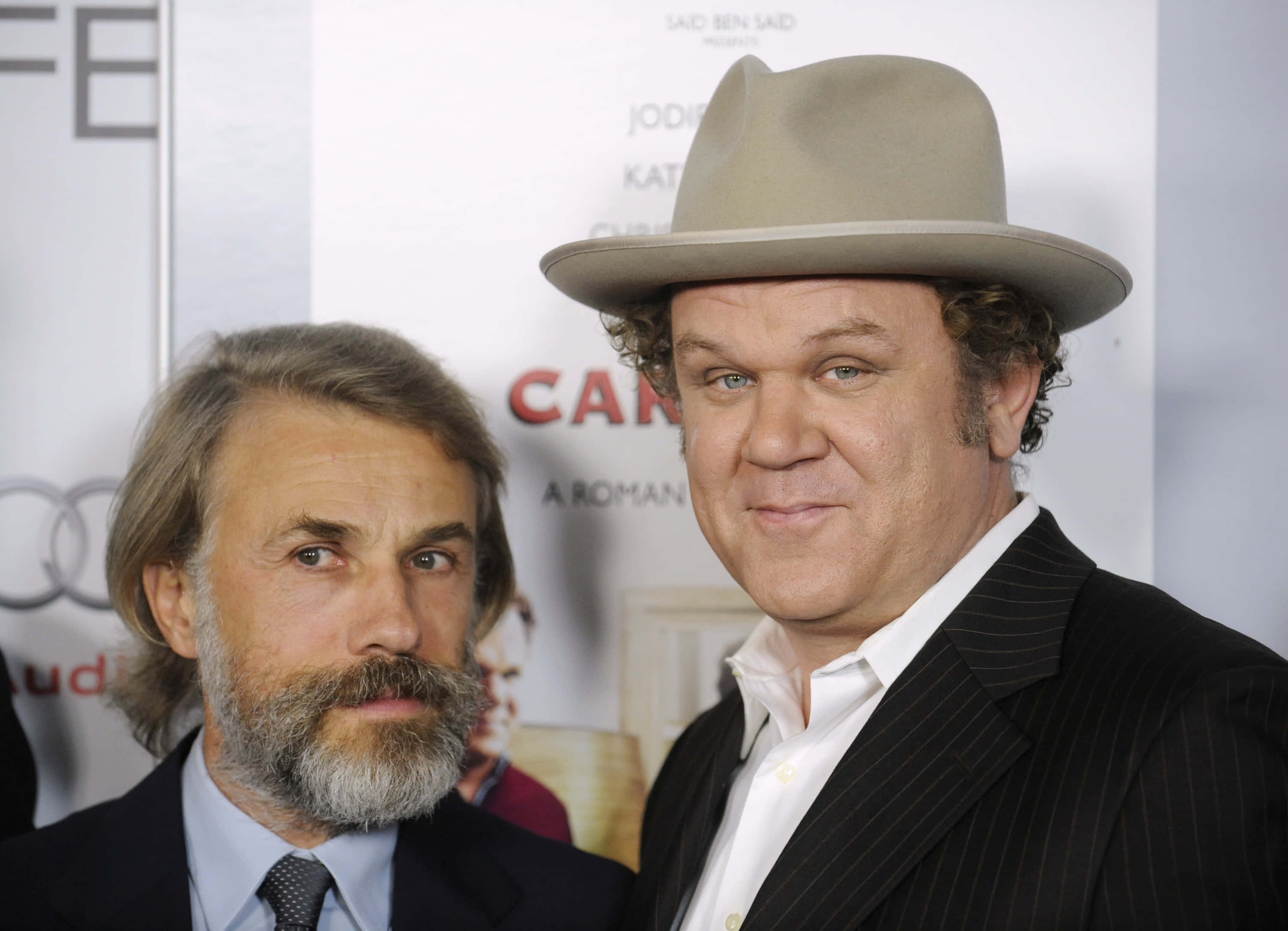 John C. Reilly 桌布 壁紙 — 兩名男子在電影首映會上擺姿勢，一人戴著軟呢帽、身穿細條紋西裝，另一人有鬍鬚、身穿西裝。