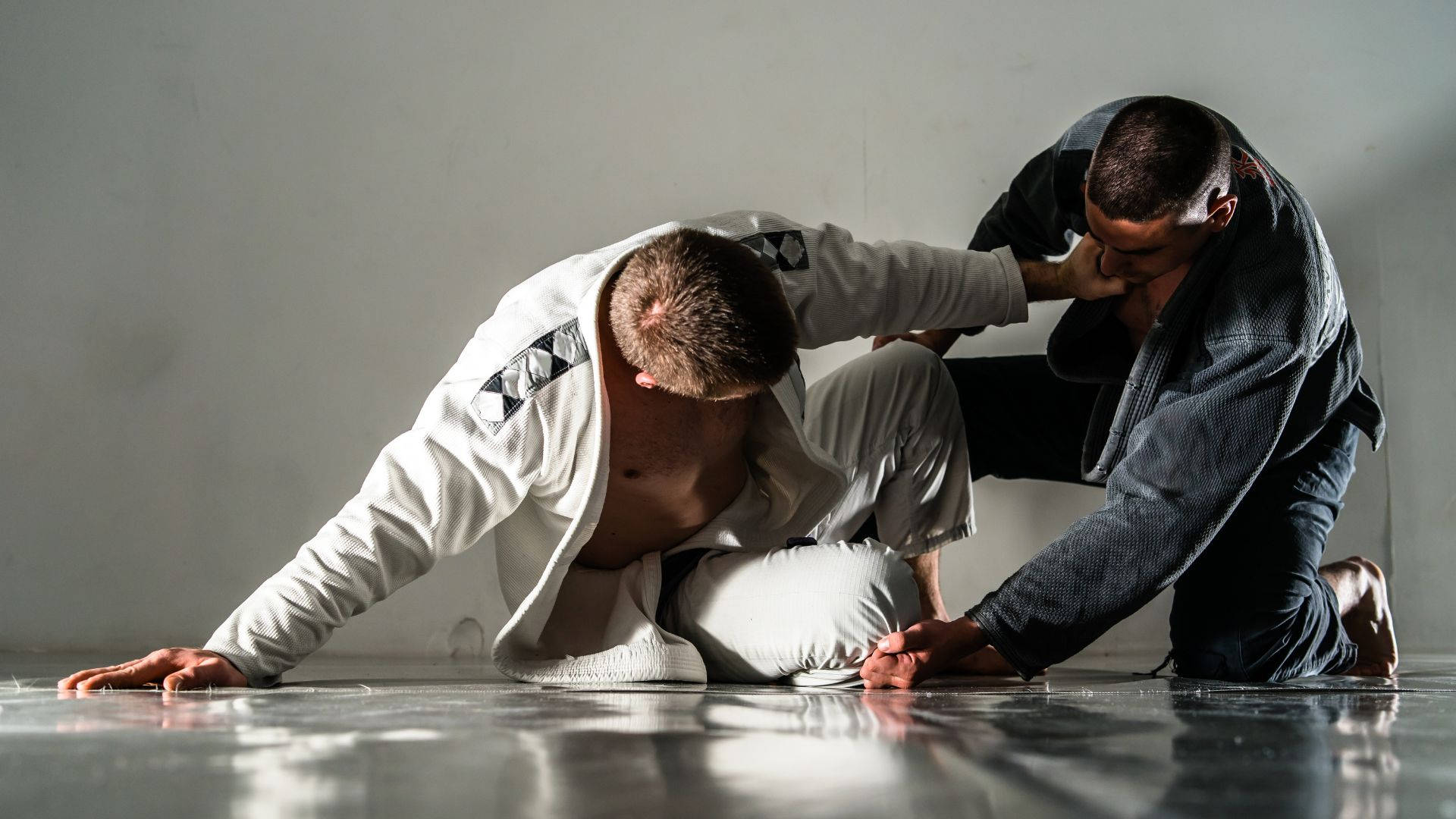 martial arts 桌布 壁紙 — 兩名男子穿著格鬥道服，在拋光地板上對著純白牆壁激烈訓練。