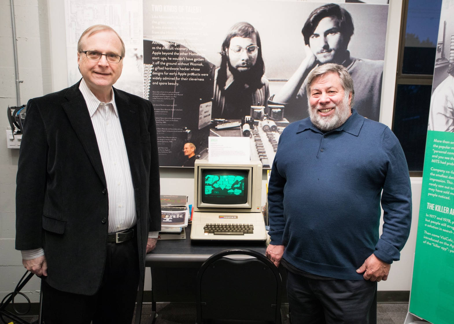 兩名微笑的男子在博物館展覽中與一部舊Apple電腦合影。 — Microsoft 壁紙