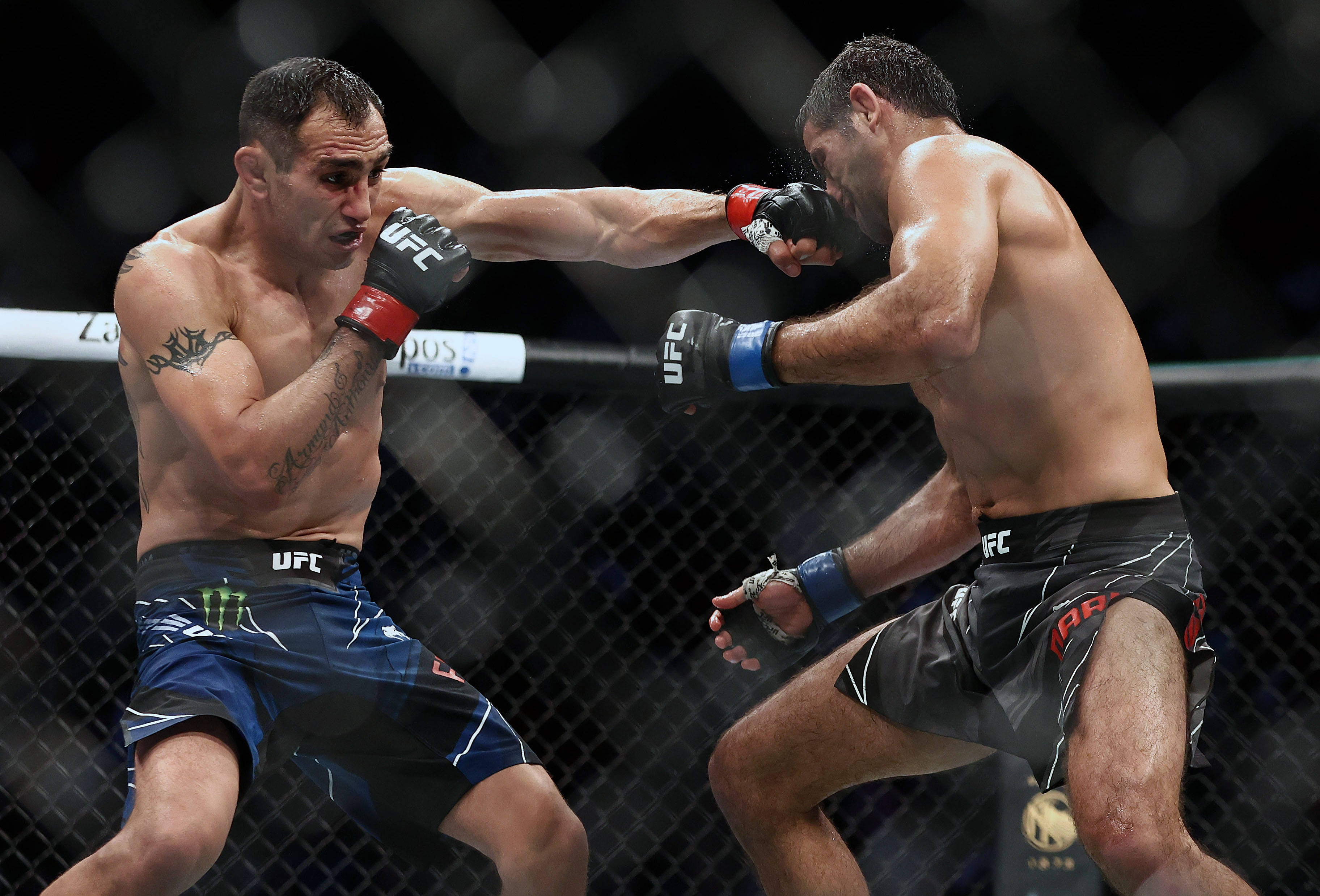 MMA 桌布 壁紙 — 兩名男性MMA拳手在明亮的場館燈光下於UFC八角籠內交換強力拳擊。