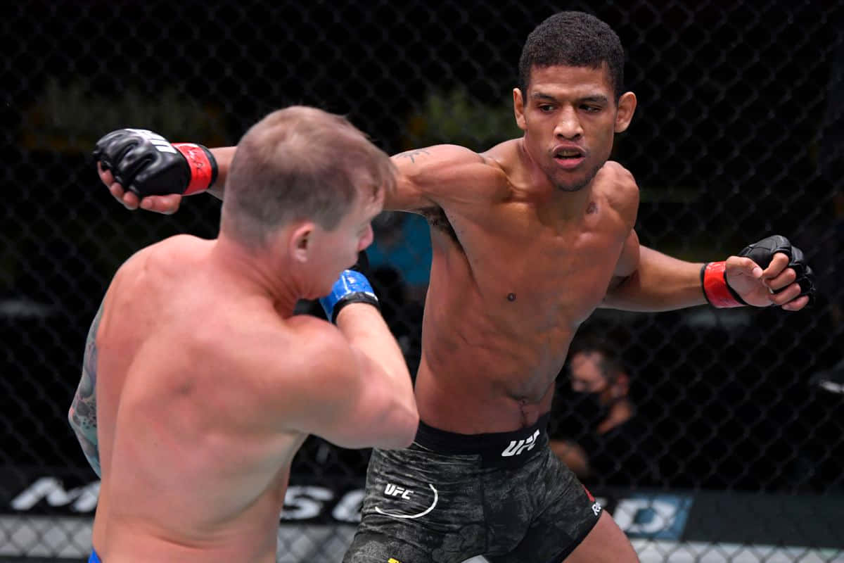 UFC 桌布 壁紙 — 兩名男性拳手在UFC八角籠中交鋒，其中一人向對手面部猛烈出拳。