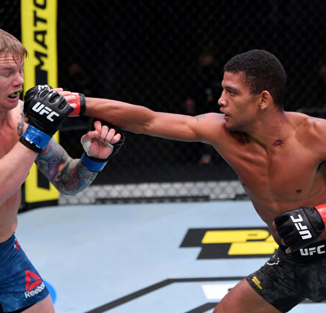 UFC 桌布 壁紙 — 兩名男性拳手在UFC八角籠中交鋒，其中一人向對手面部猛烈出拳。