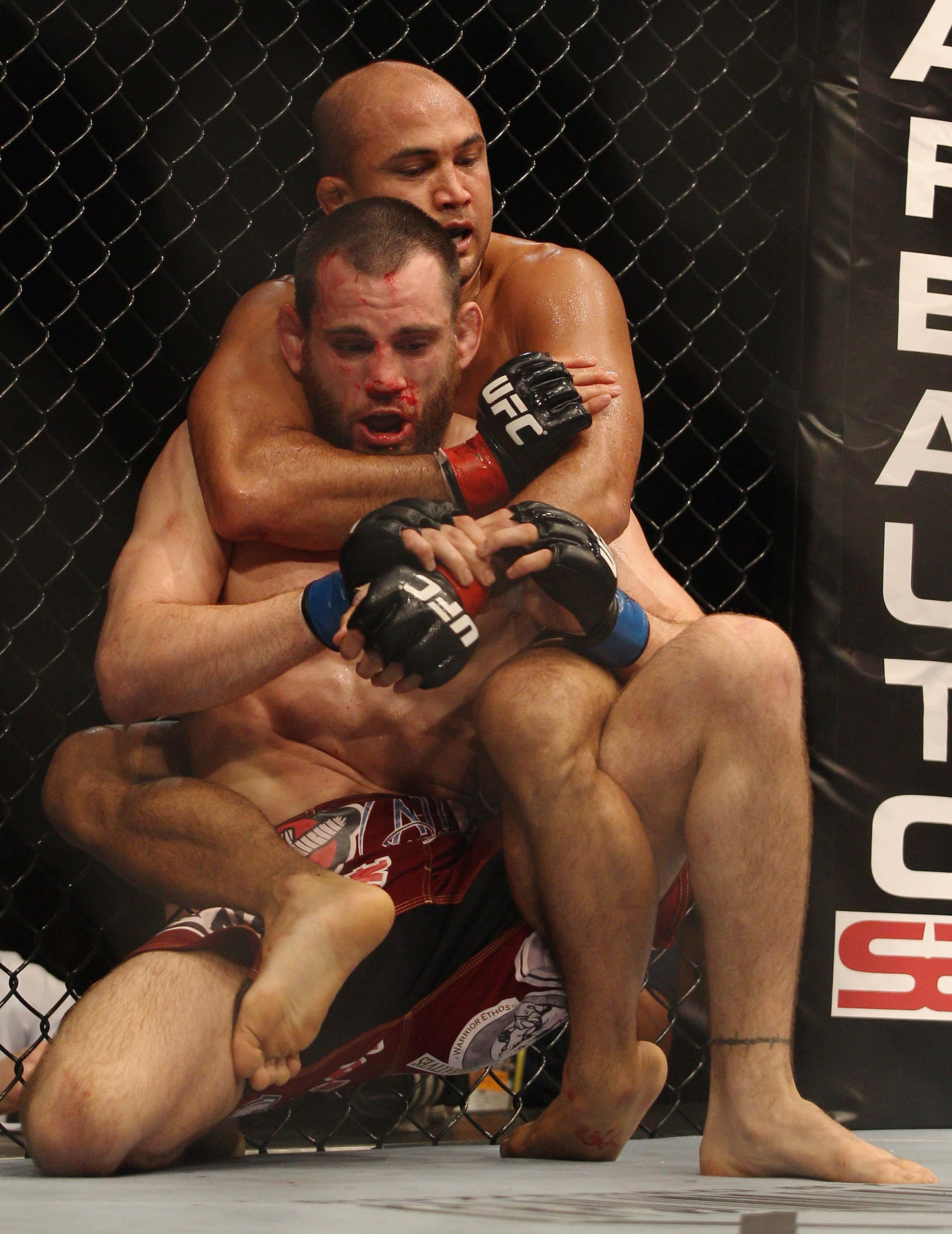 UFC 桌布 壁紙 — 兩名男性拳手在UFC八角籠內激烈纏鬥，滿臉鮮血，肌肉緊繃。