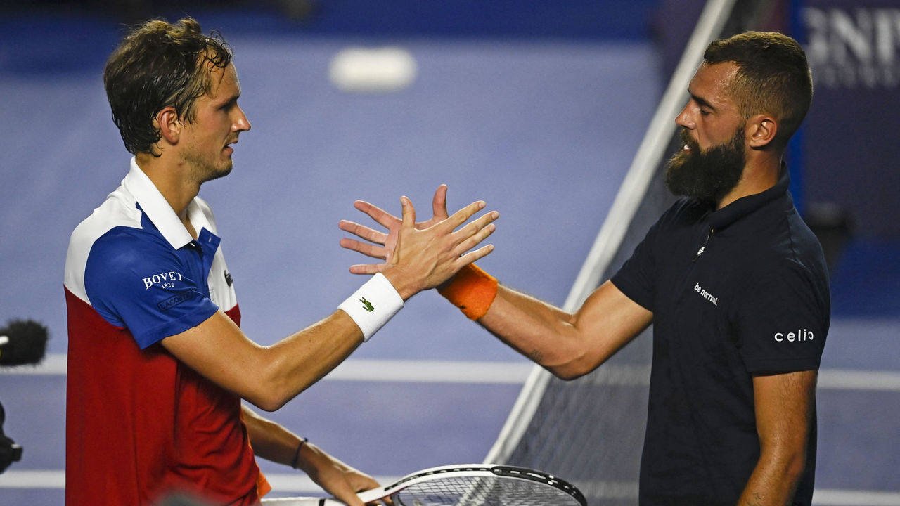 Tennis 桌布 壁紙 — 兩名男性網球運動員在明亮的體育場燈光下，在藍色硬地球場上互相擊掌。