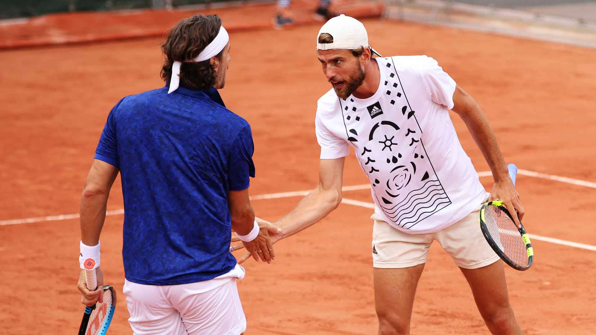 Tennis 桌布 壁紙 — 兩名男網球選手在陽光明媚的紅土球場上賽後握手。