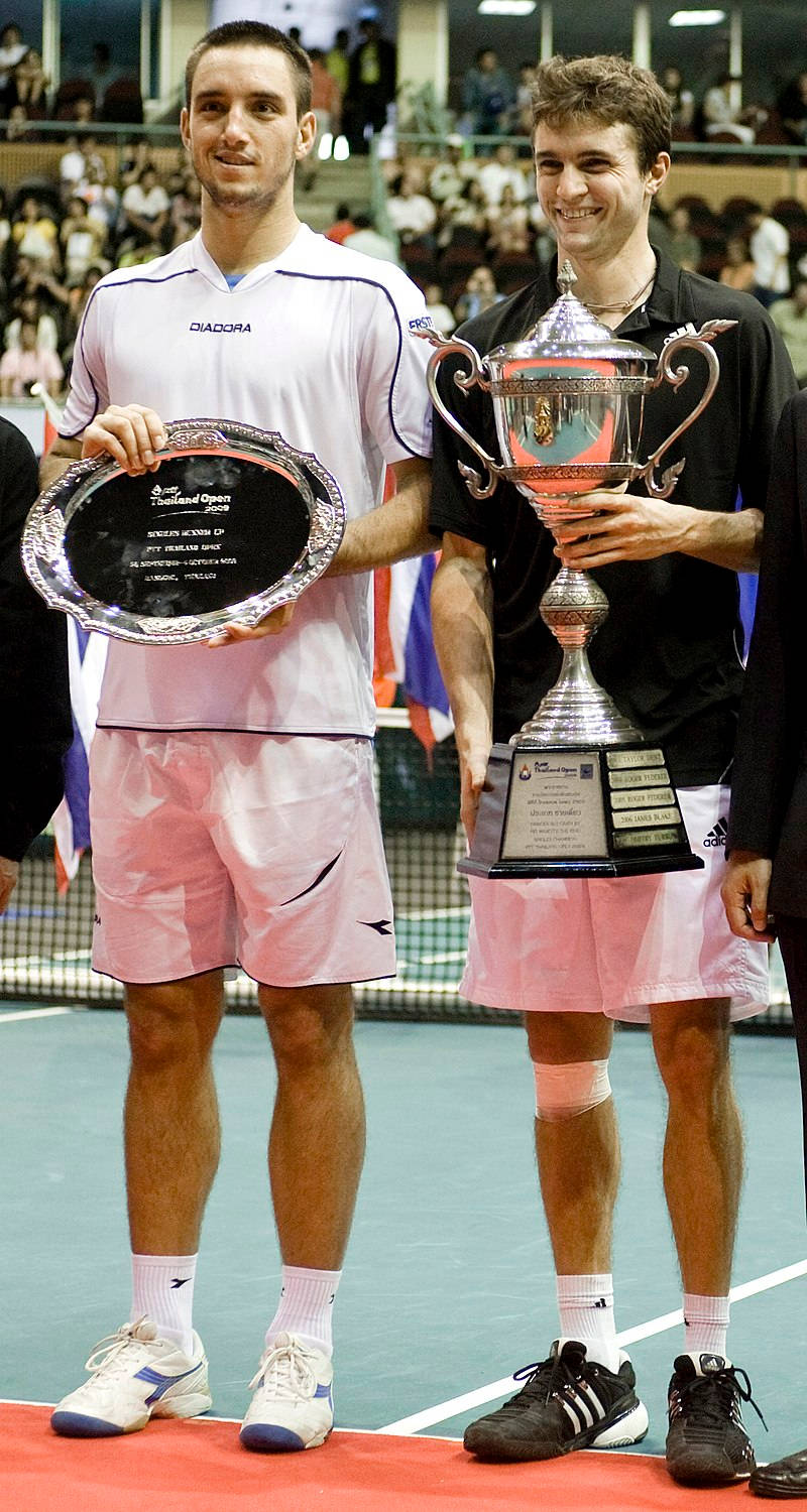 Trophy 桌布 壁紙 — 兩名男網球選手站在球場上，手持獎盃，一個銀盃和一個獎牌，背景有群眾。