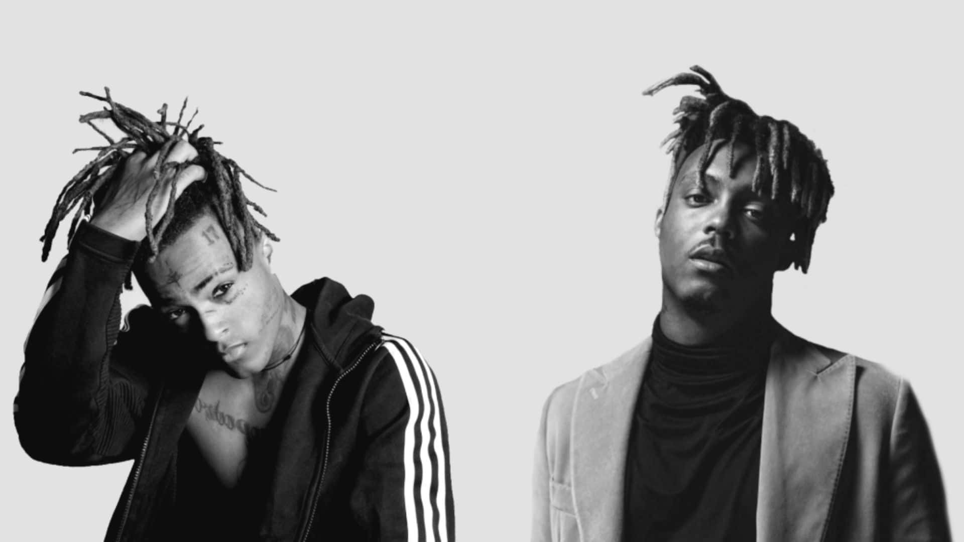 Rappers 桌布 壁紙 — 兩名留著辮子的男士在純色背景前擺姿勢，一隻手放在頭上，另一隻手靜止，一人穿連帽衫，一人穿西裝外套，兩人均為黑白。
