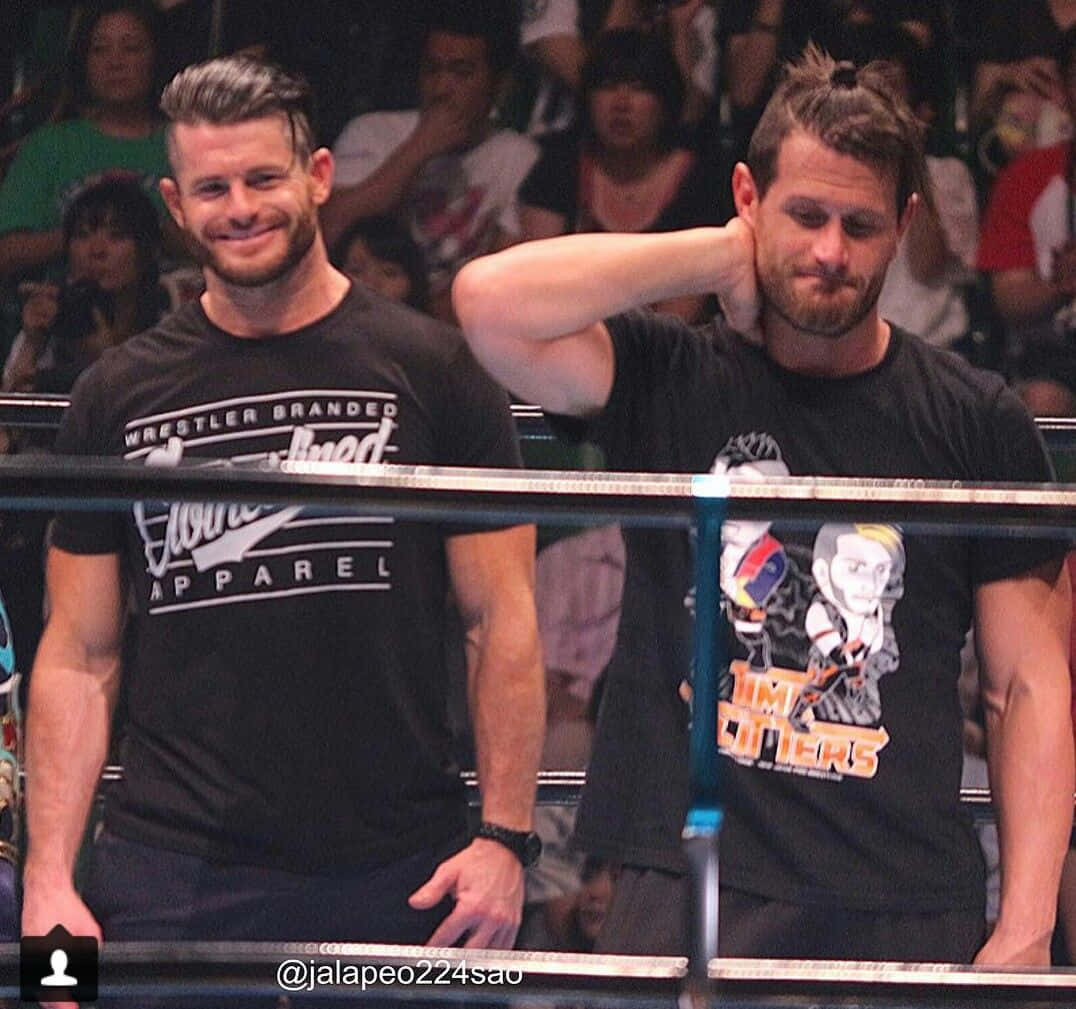 WWE 桌布 壁紙 — 兩名留鬍鬚的摔角手身穿黑色T恤，站在擂台上，背後有群眾。