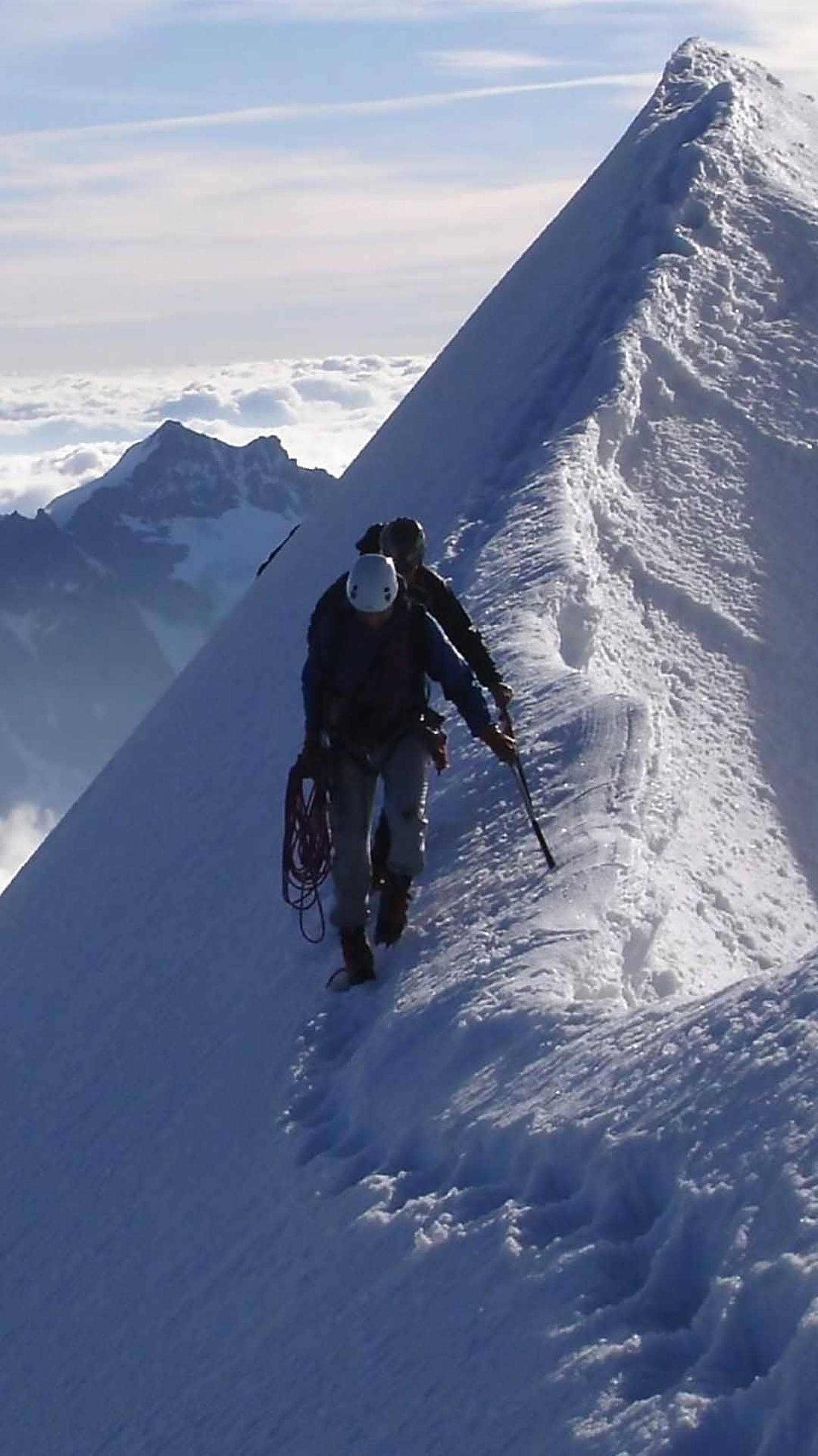 Hiking 桌布 壁紙 — 兩名登山者帶著冰爪和冰鎬，在雲海之上攀登陡峭的積雪山脊。