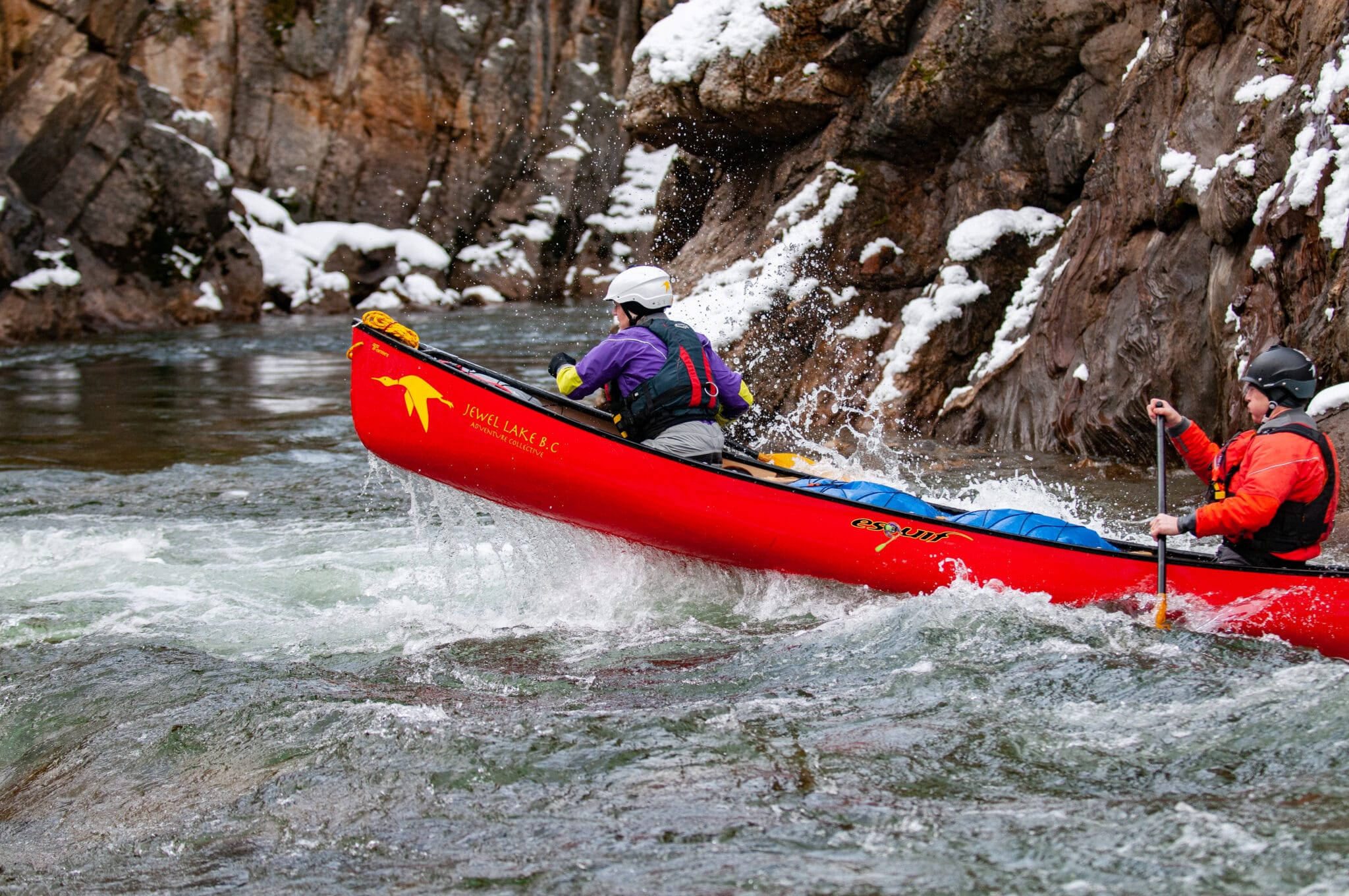 Rowing 桌布 壁紙 — 兩名皮划艇運動員划著紅色獨木舟穿過湍急的河流急流，身後是白雪覆蓋的懸崖。