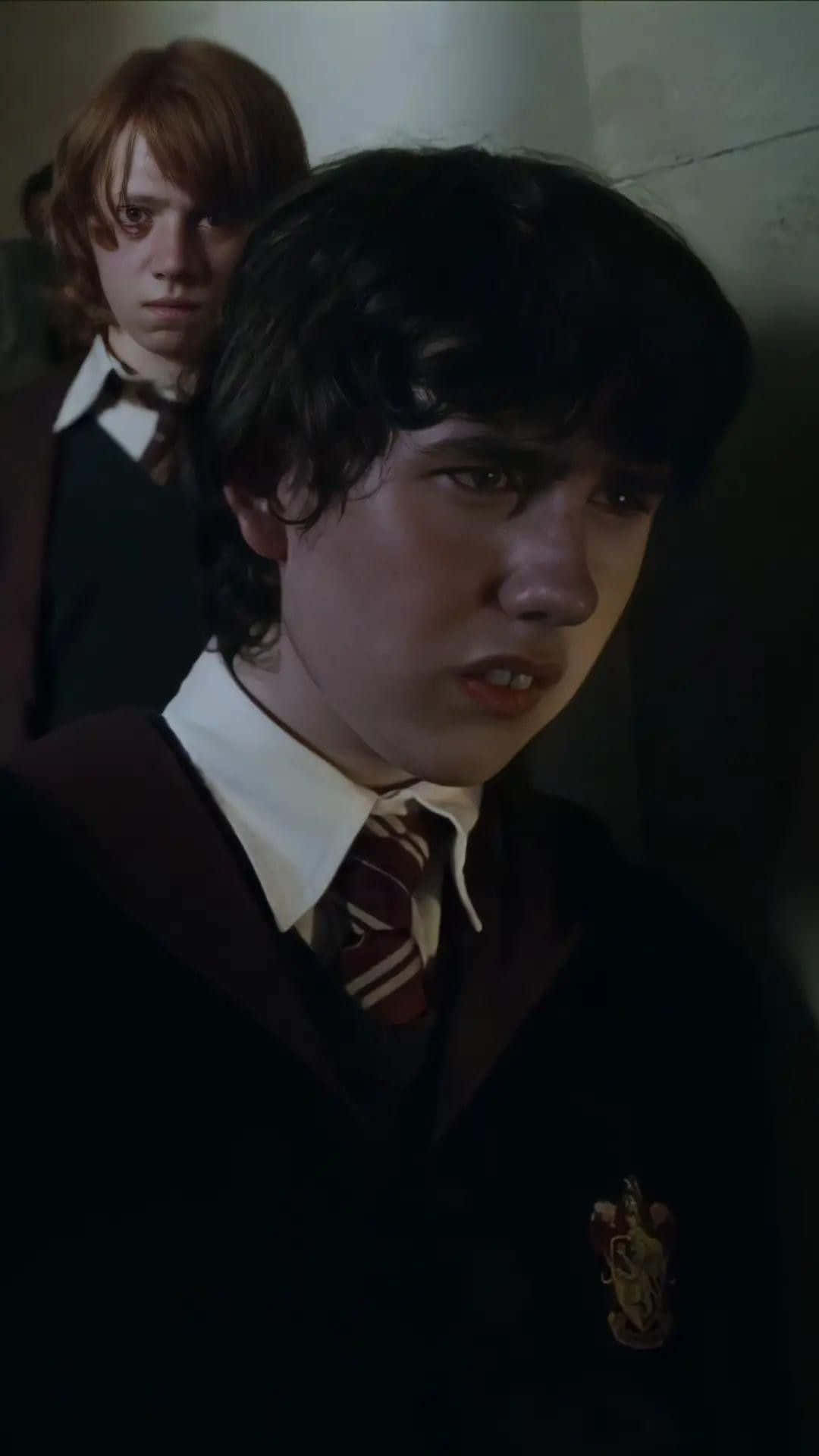 Neville Longbottom 桌布 壁紙 — 兩名穿著霍格華茲制服的年輕巫師在燈光昏暗的走廊上看起來緊張又擔心。