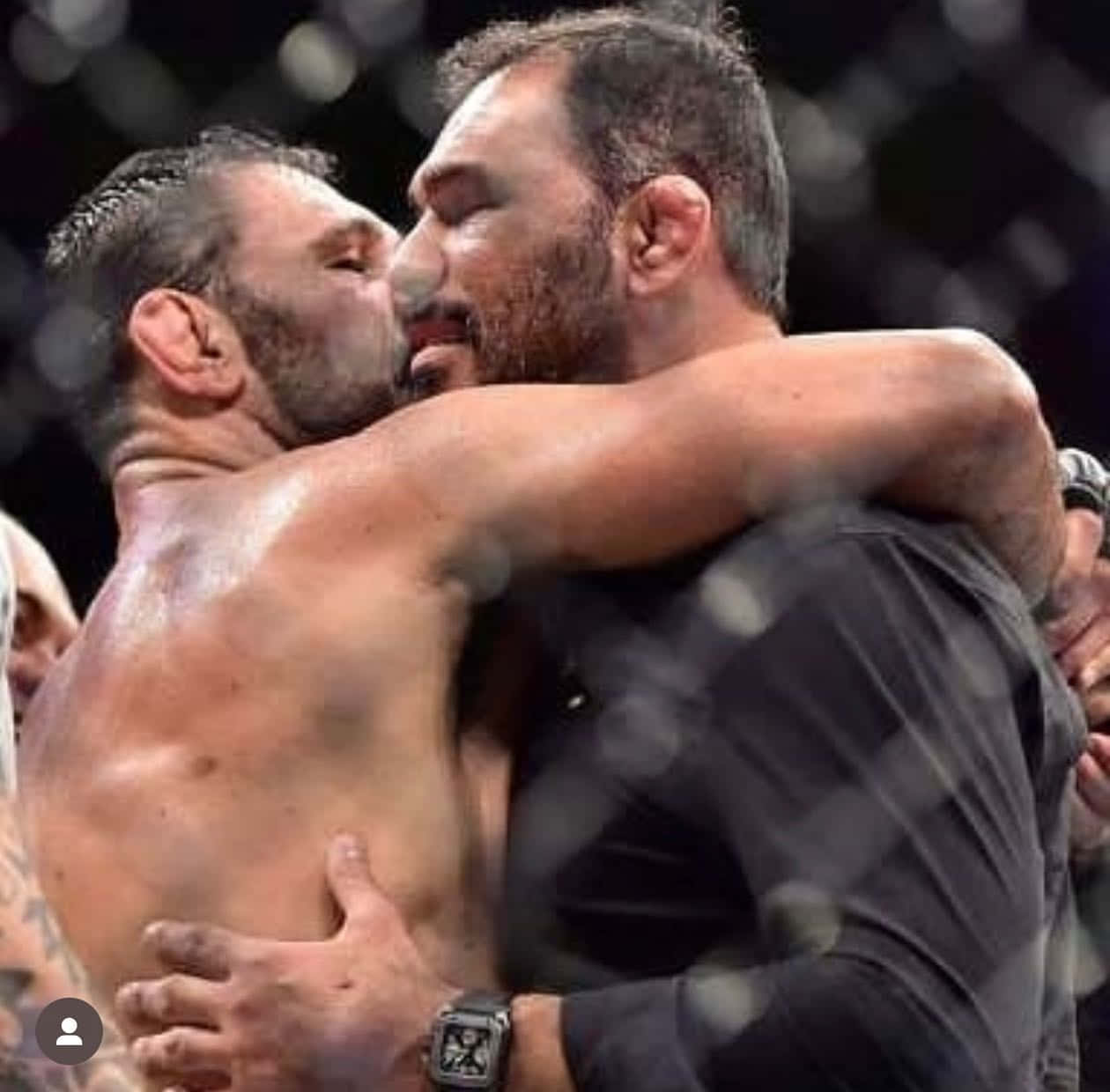 UFC 桌布 壁紙 — 兩名筋疲力竭的拳手在明亮的場館燈光下，於鐵籠內進行一場殘酷的MMA比賽後緊緊擁抱。