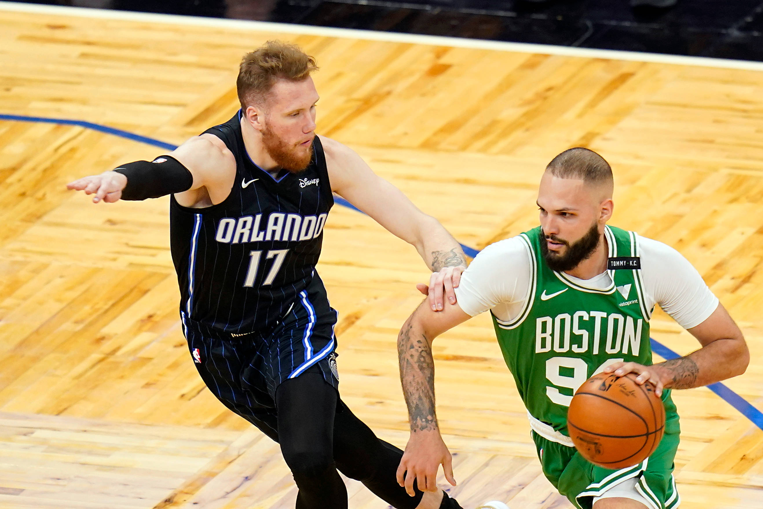 NBA 桌布 壁紙 — 兩名籃球運動員在拋光木地板上激烈競爭，一名身穿綠色球衣運球，另一名身穿黑色球衣積極防守。