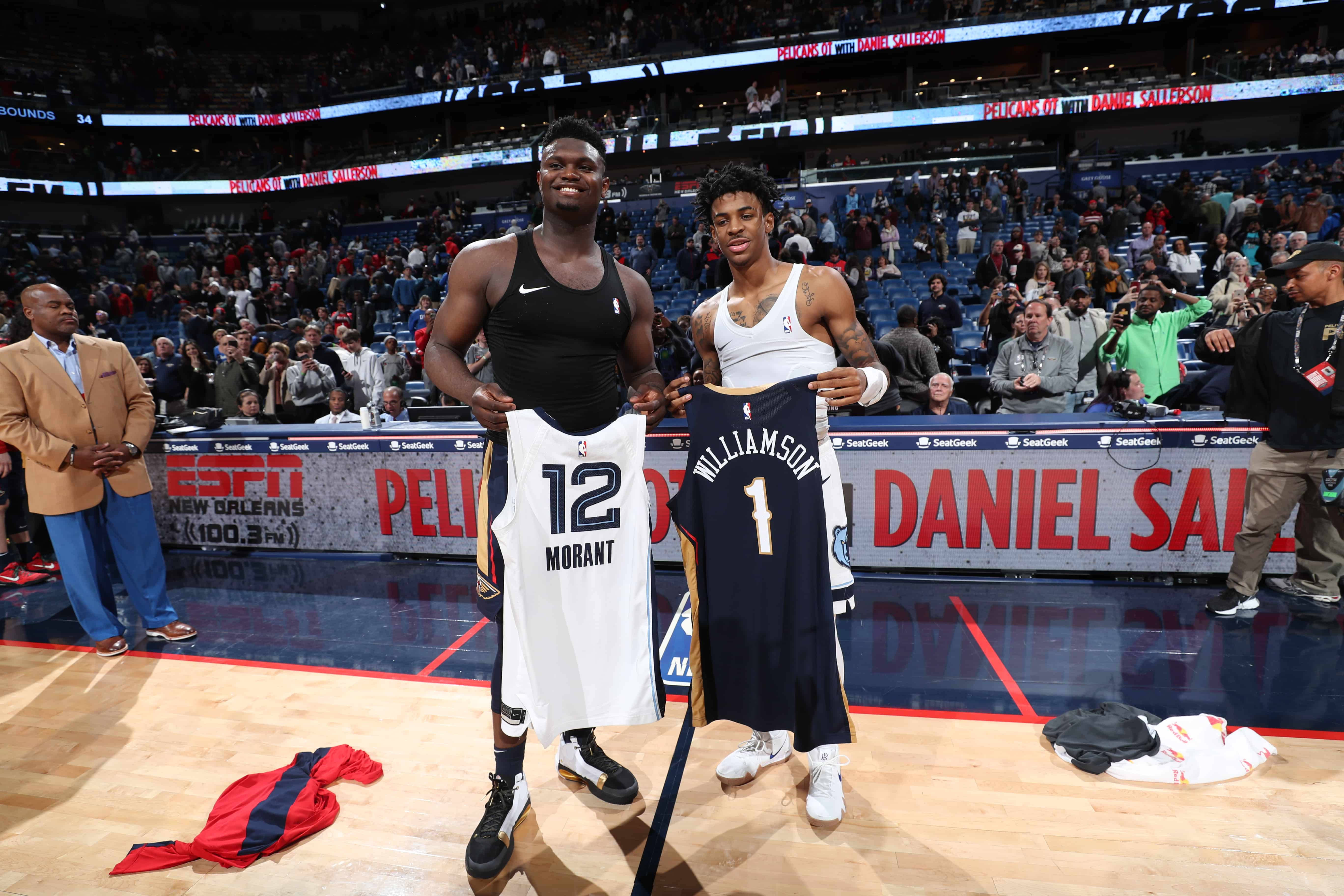 Zion 桌布 壁紙 — 兩名籃球運動員在擠滿球迷和ESPN品牌的球場上微笑著舉起他們的新球衣。