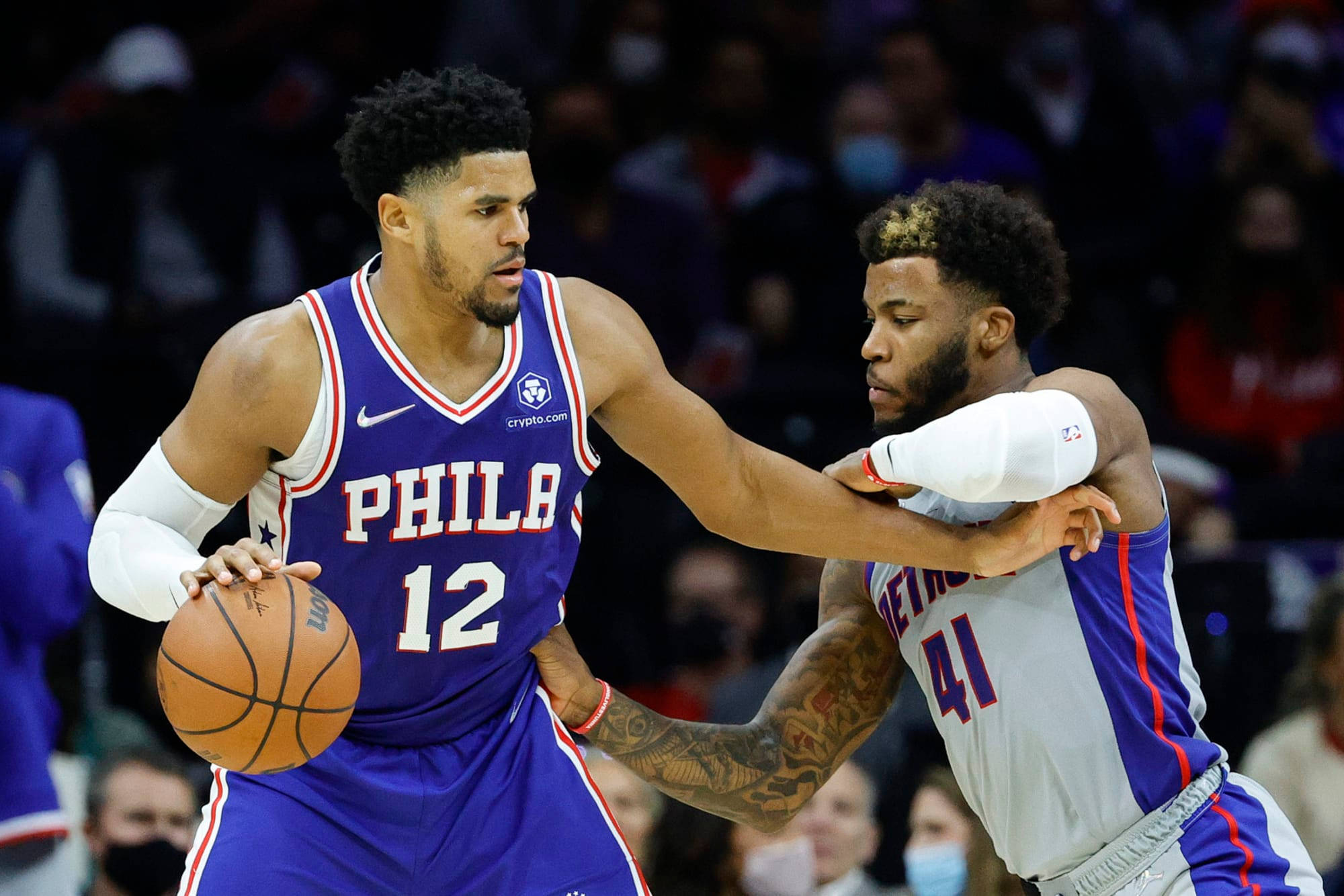 76ers 桌布 壁紙 — 兩名籃球運動員在明亮的場館燈光下，於職業比賽中激烈爭奪球權。