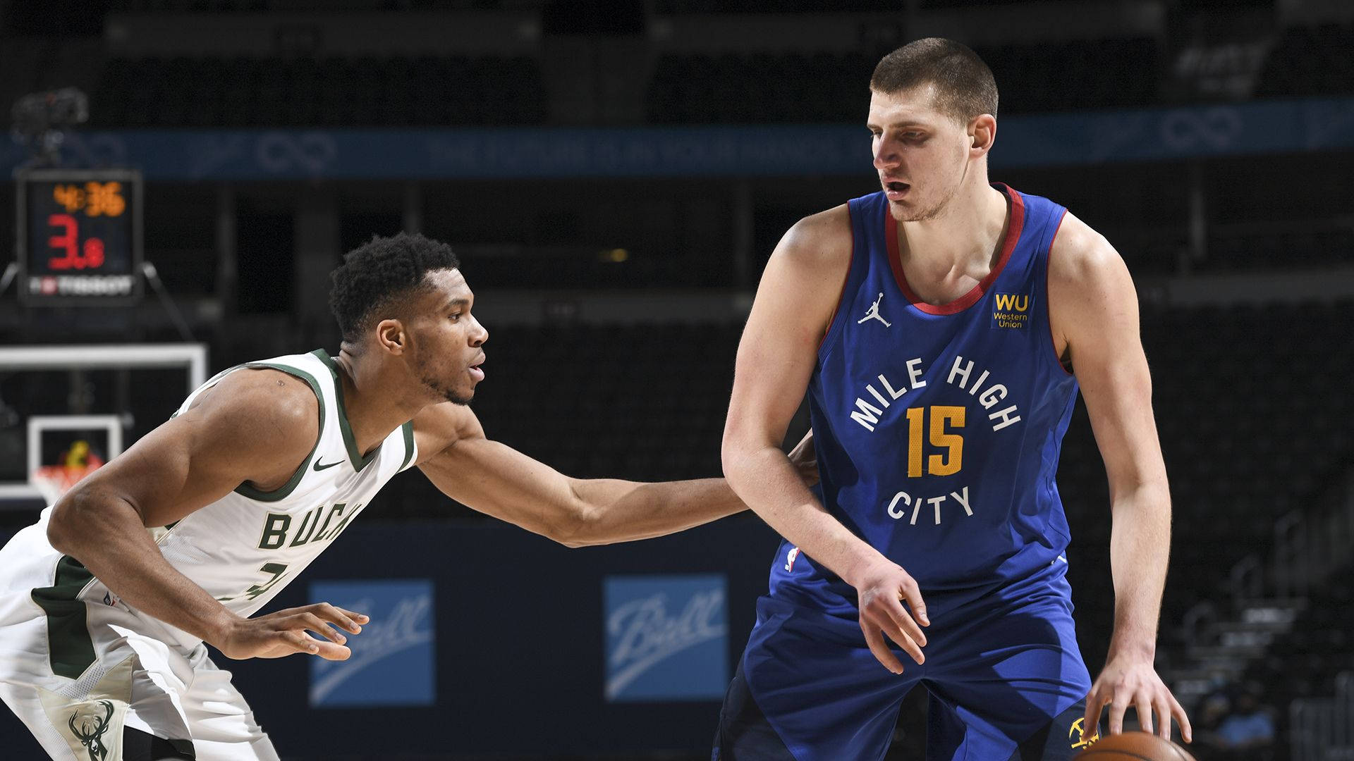 Jokic 桌布 壁紙 — 兩名籃球運動員在比賽中激烈競爭，一名身穿白色球衣防守另一名身穿藍色球衣持球的球員。