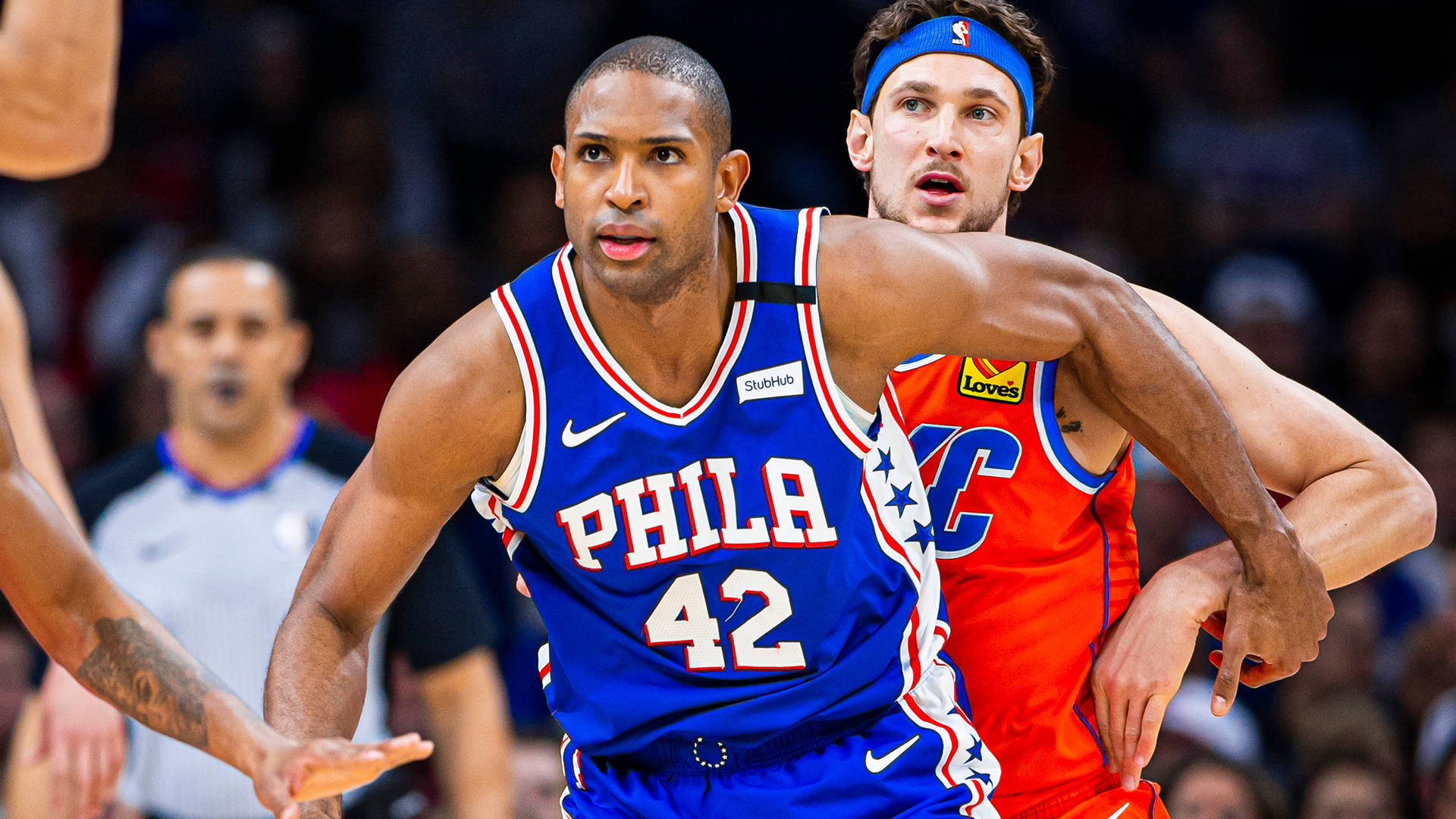 Al Horford 桌布 壁紙 — 兩名籃球運動員在比賽中激烈競爭，一人身穿藍色PHILA球衣42號，另一人身穿帶橙色點綴的紅色球衣。