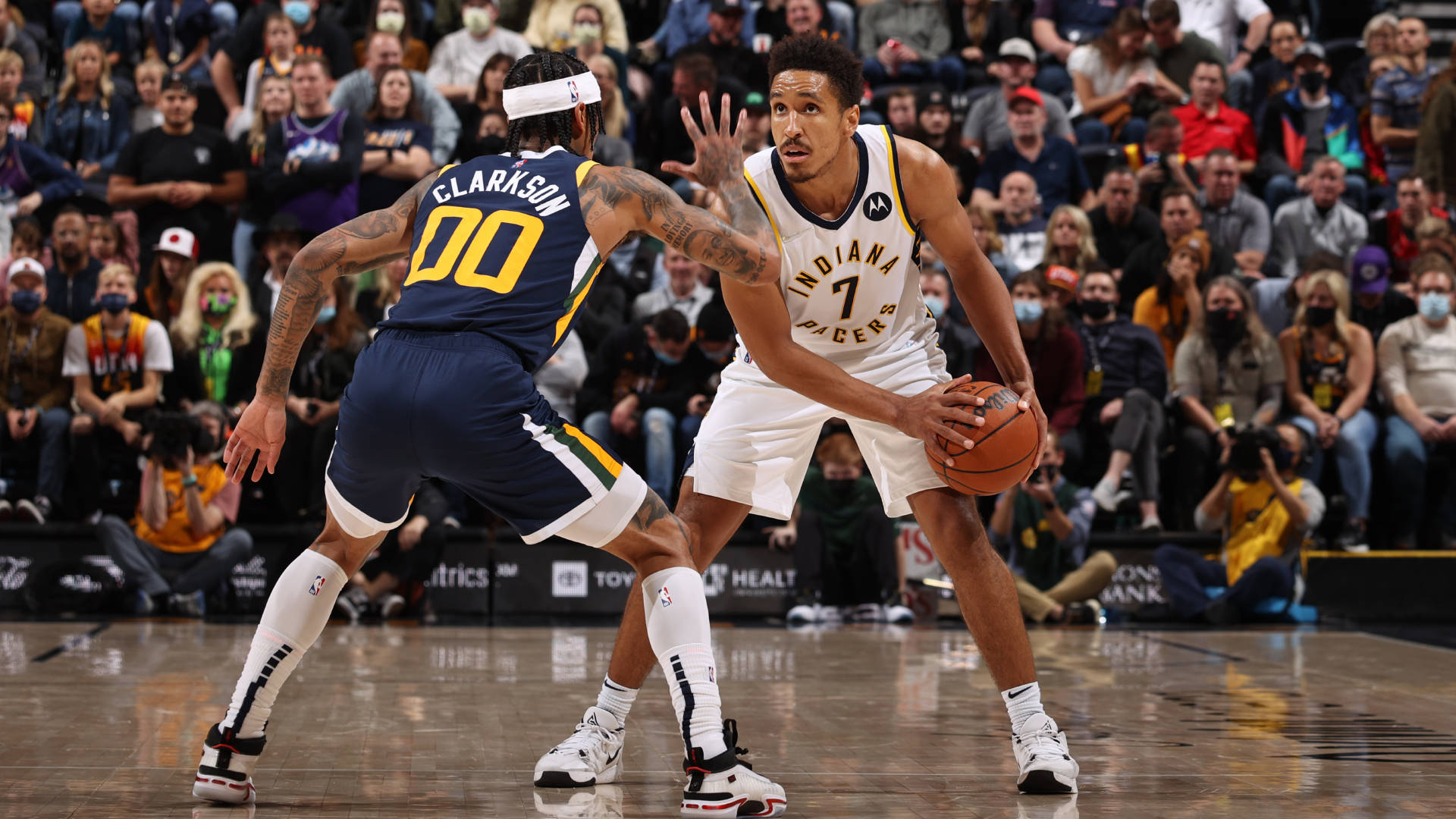 malcolm brogdon 桌布 壁紙 — 兩名籃球運動員在職業比賽中激烈爭奪位置，背景是擠滿的人群。