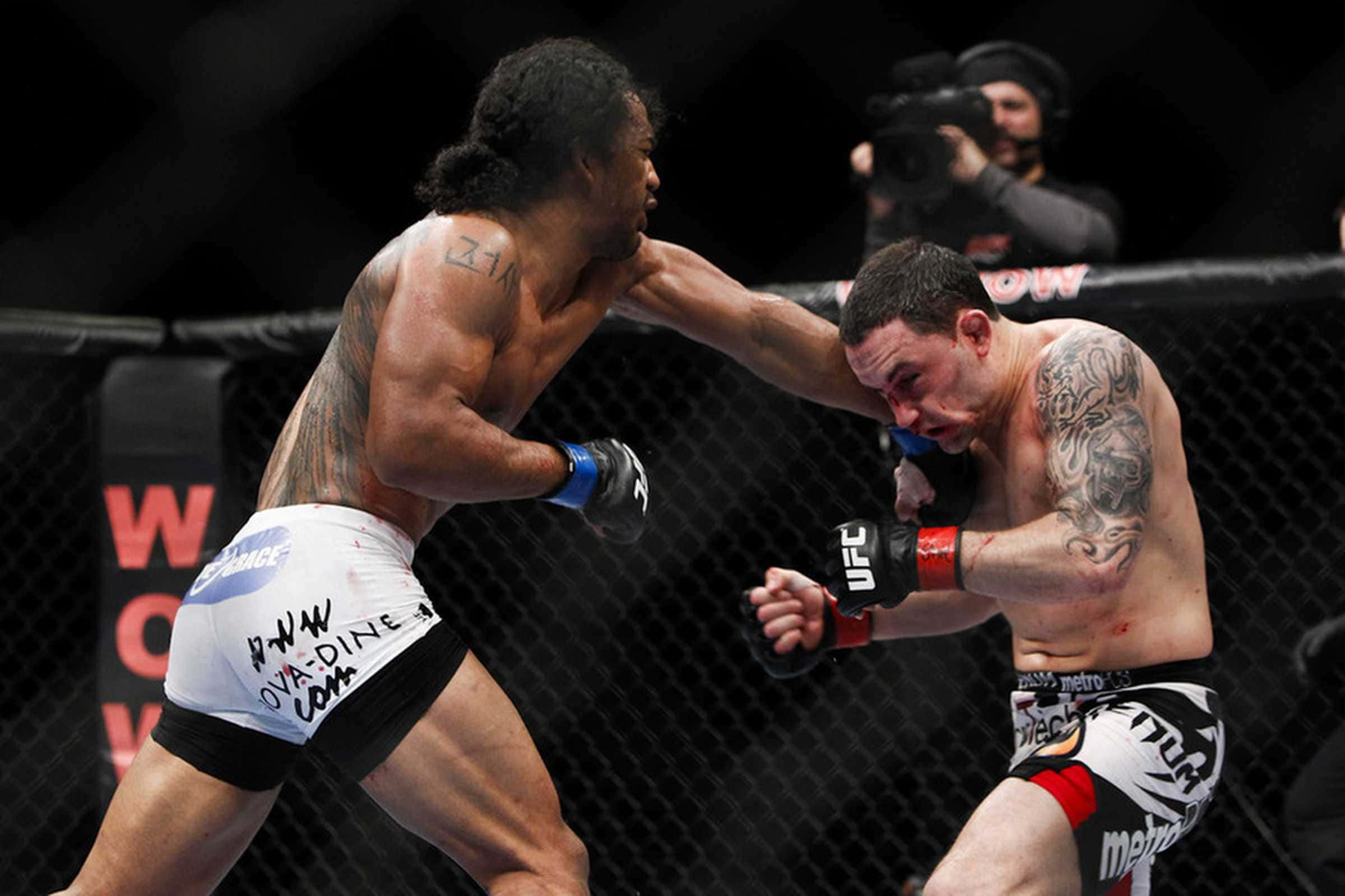 MMA 桌布 壁紙 — 兩名紋身MMA拳手在明亮的場館燈光下進行激烈的籠鬥，血汗飛濺。