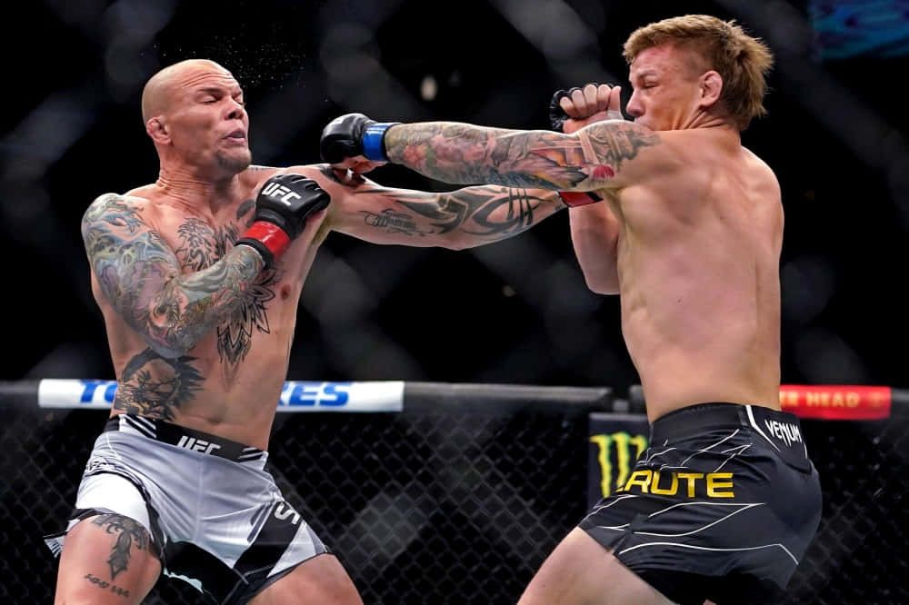 UFC 桌布 壁紙 — 兩名紋身MMA拳手在激烈的鐵籠比賽中交鋒，汗水飛濺，其中一人打出強力一拳。