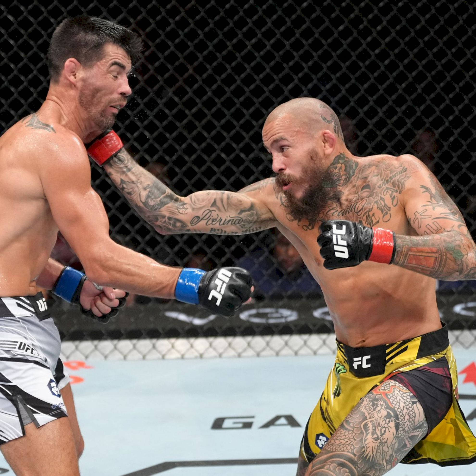 UFC 桌布 壁紙 — 兩名紋身MMA拳手在籠中交鋒，一人打出強力一拳，另一人阻擋。
