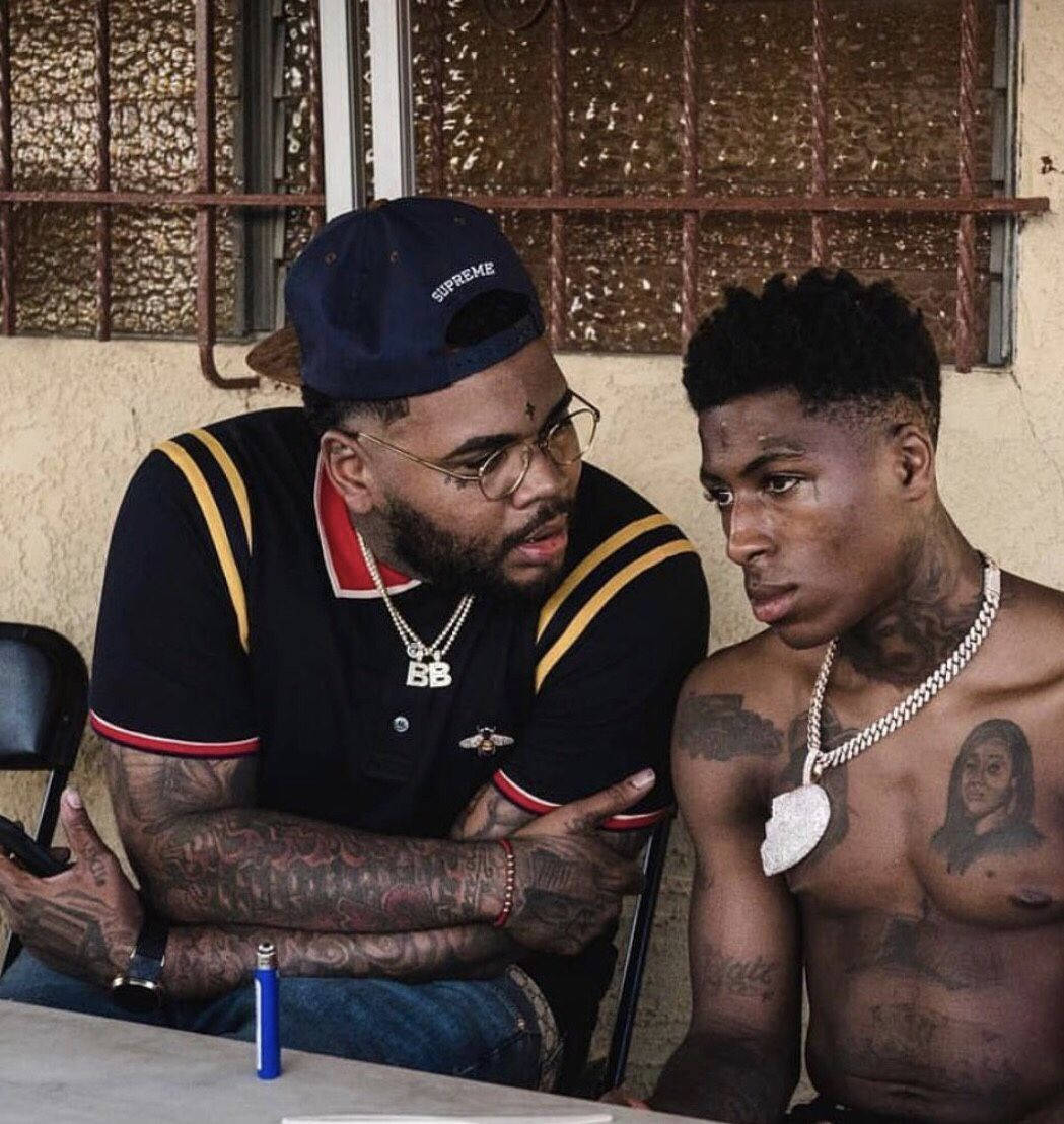 Kevin Gates 桌布 壁紙 — 兩名紋身男子坐在桌旁，一人戴著Supreme帽和眼鏡，另一人赤裸上身，胸口有肖像紋身。